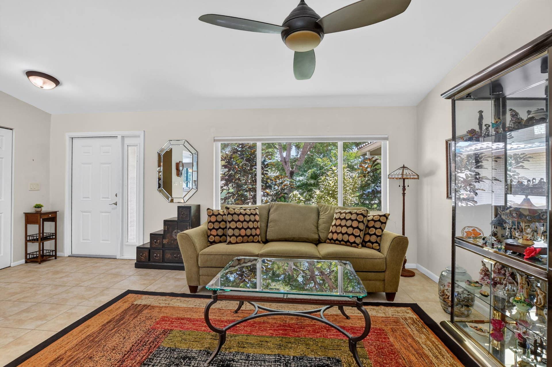 Bright living space featuring a ceiling fan, tiled flooring, and a window with exterior views