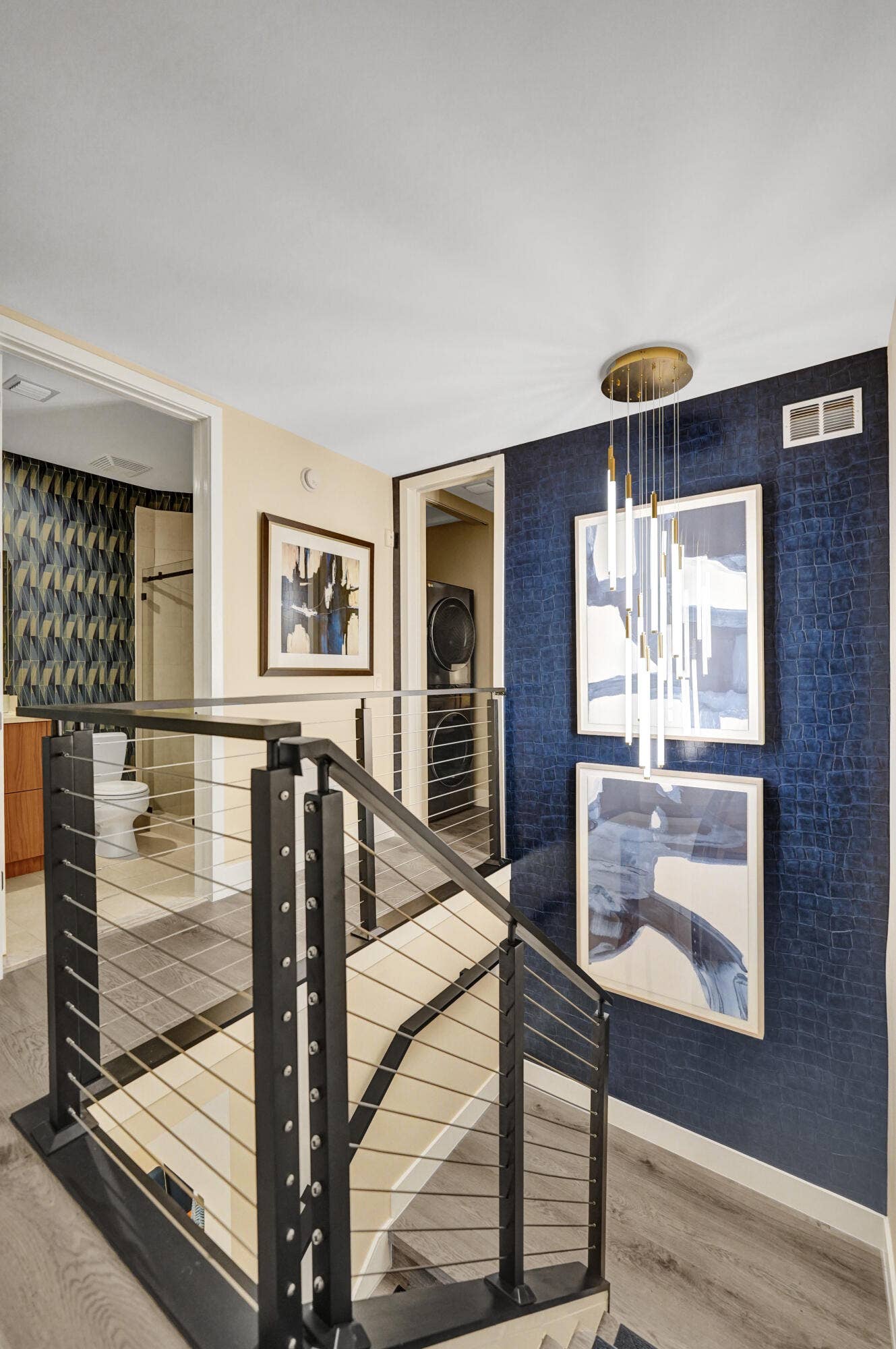 Modern cable railing system, wood-finish flooring, deep blue accent wall, and contemporary ceiling light fixture