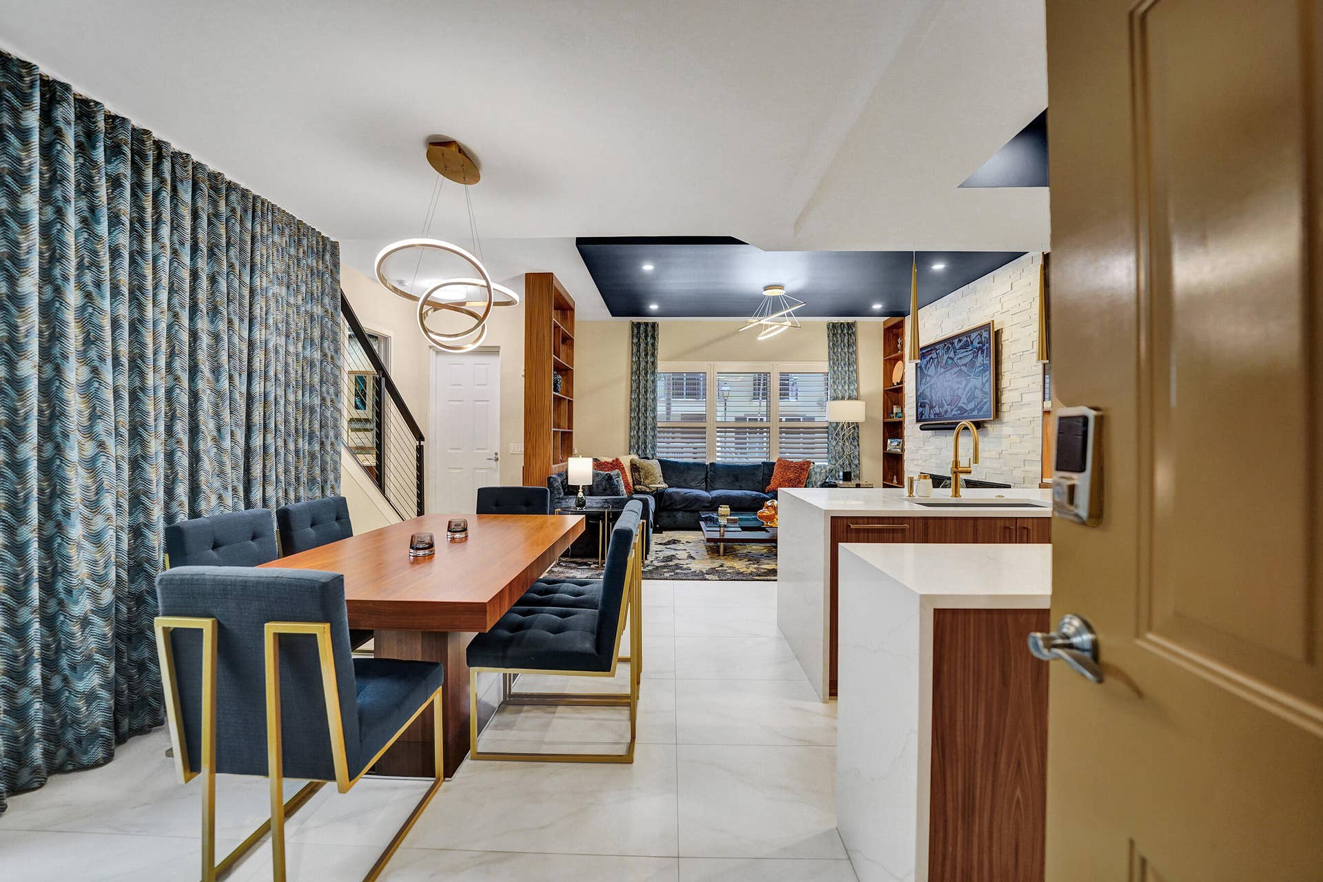 Open-concept living area featuring a kitchen island with white countertops, wood-finish cabinetry, and a gold-finish faucet