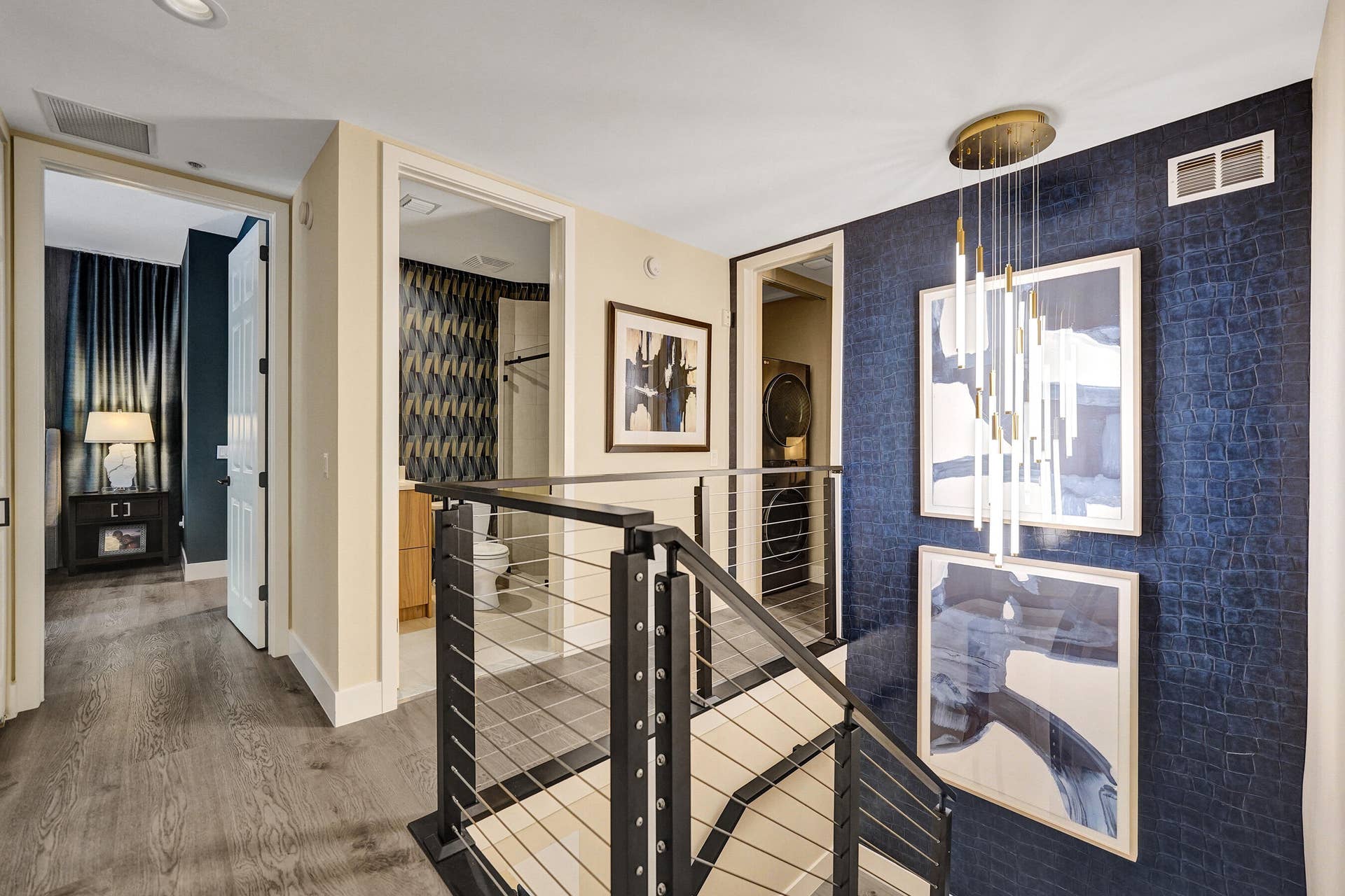 Modern cable railing system, wood-finish flooring, recessed lighting, and a contemporary chandelier