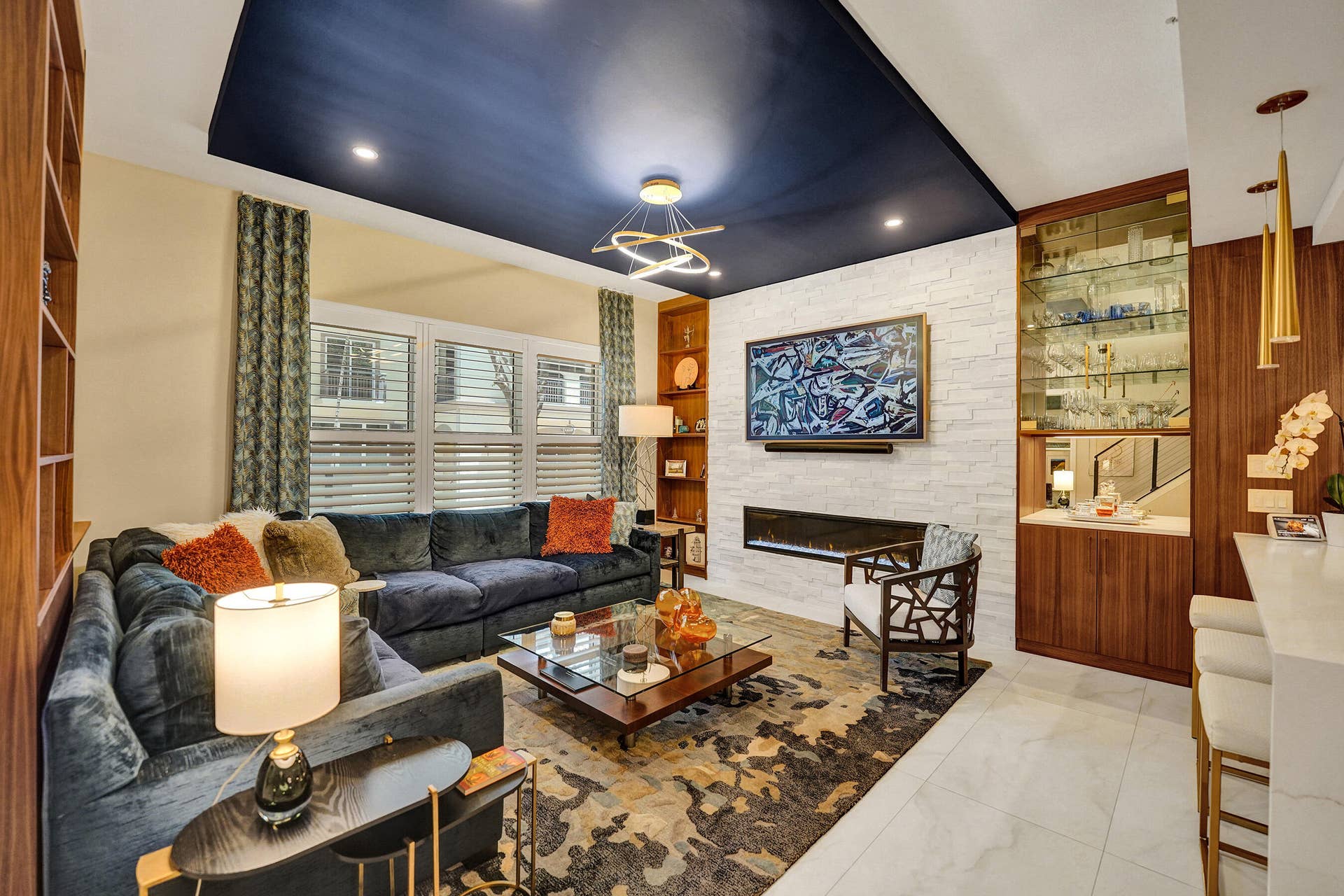 Built-in media center with linear fireplace, integrated shelving, and a wet bar featuring glass-front cabinetry