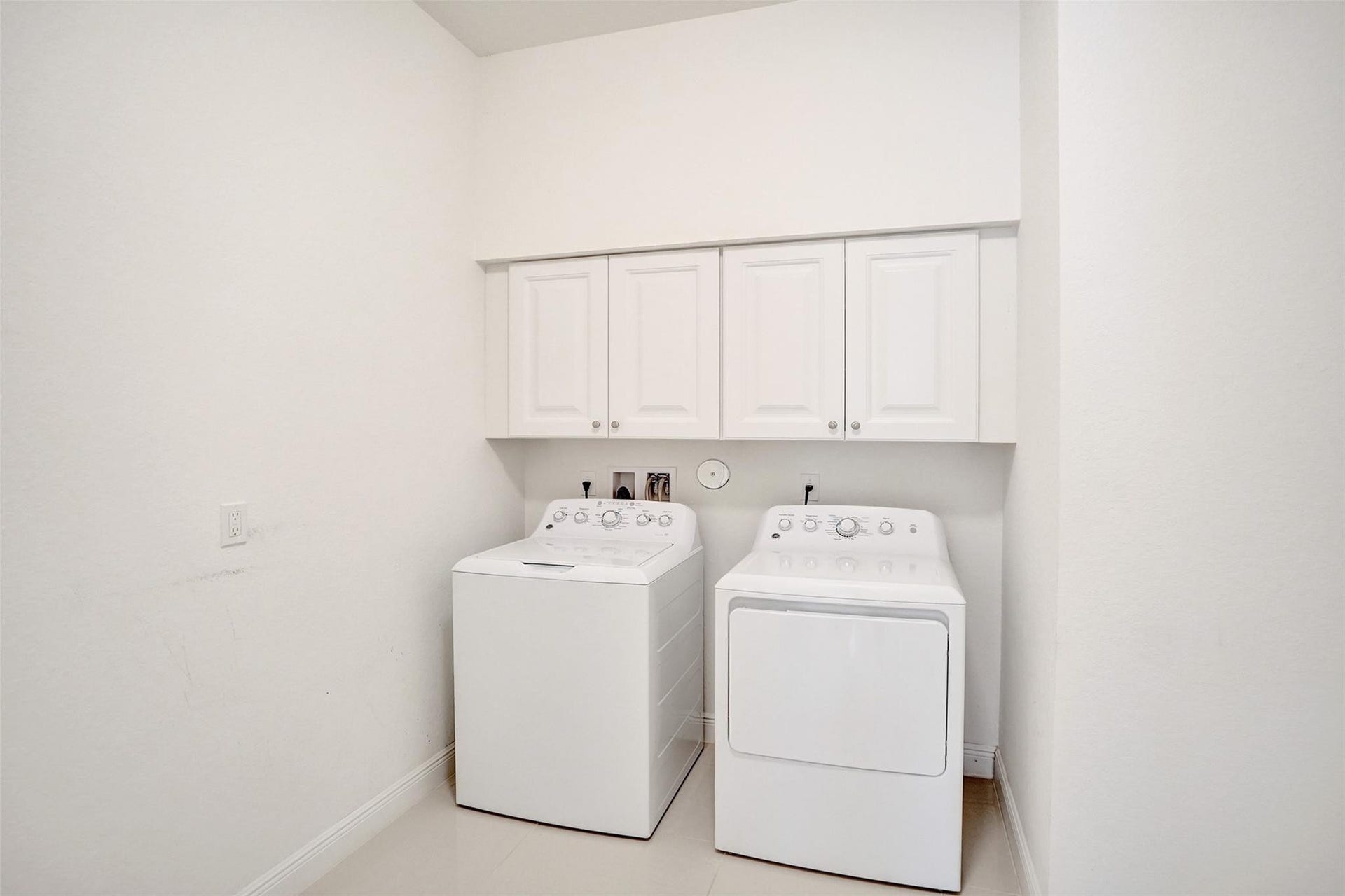 9749 Blue Isle, #BAY, Parkland, FL 33076 White cabinetry with panel doors, integrated washer and dryer, and tile flooring