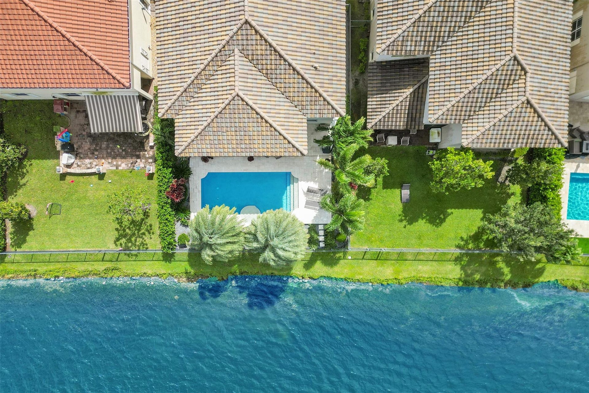 9749 Blue Isle, #BAY, Parkland, FL 33076 Waterfront property featuring a private swimming pool, green lawn, and mature palm trees