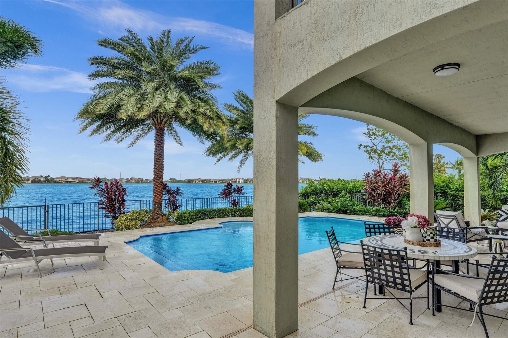 9749 Blue Isle, #BAY, Parkland, FL 33076 Expansive pool deck with pavers, a built-in swimming pool, a covered outdoor living area, and waterfront access with a metal fence