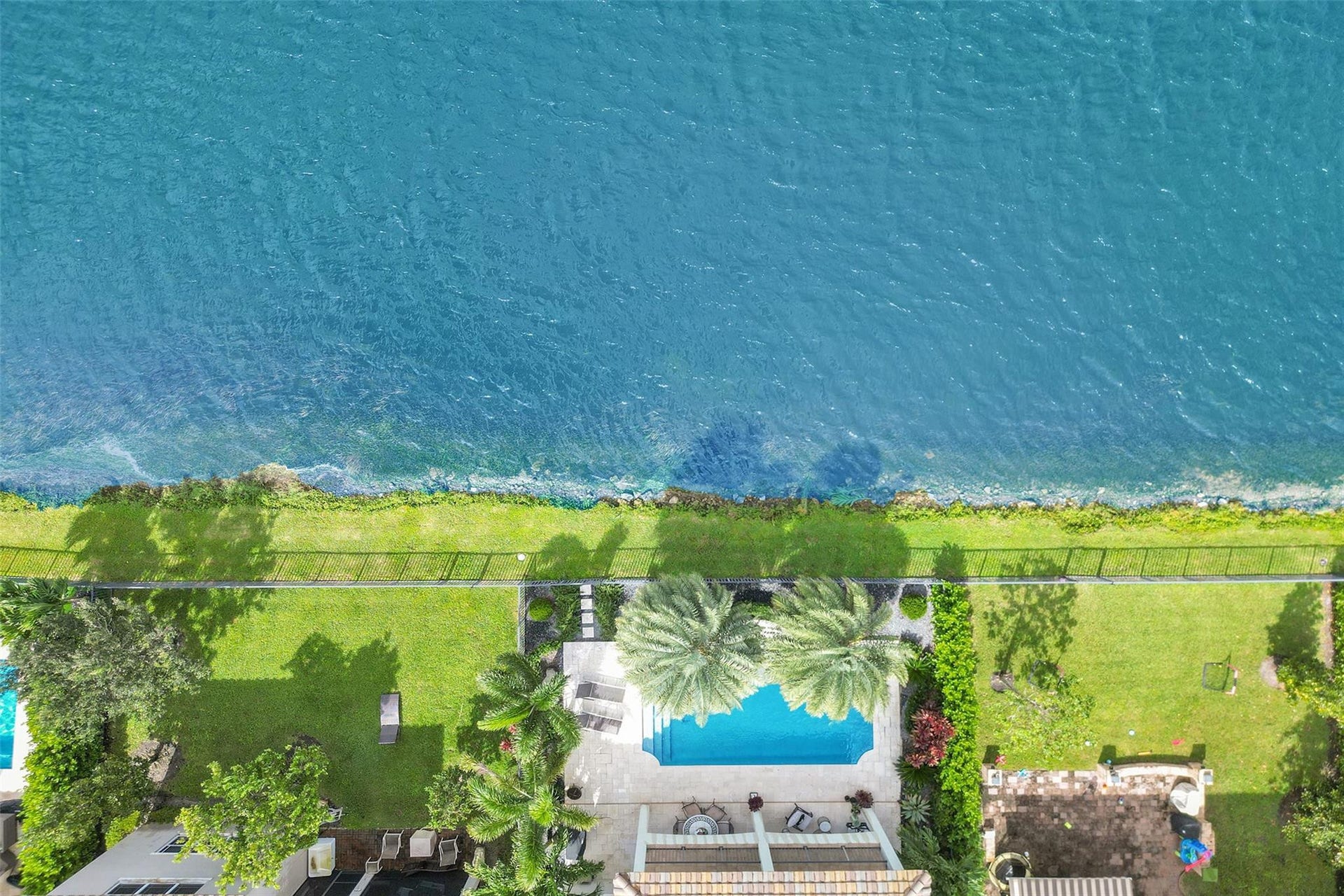 9749 Blue Isle, #BAY, Parkland, FL 33076 Waterfront property with a private swimming pool, expansive lawn, and established landscaping