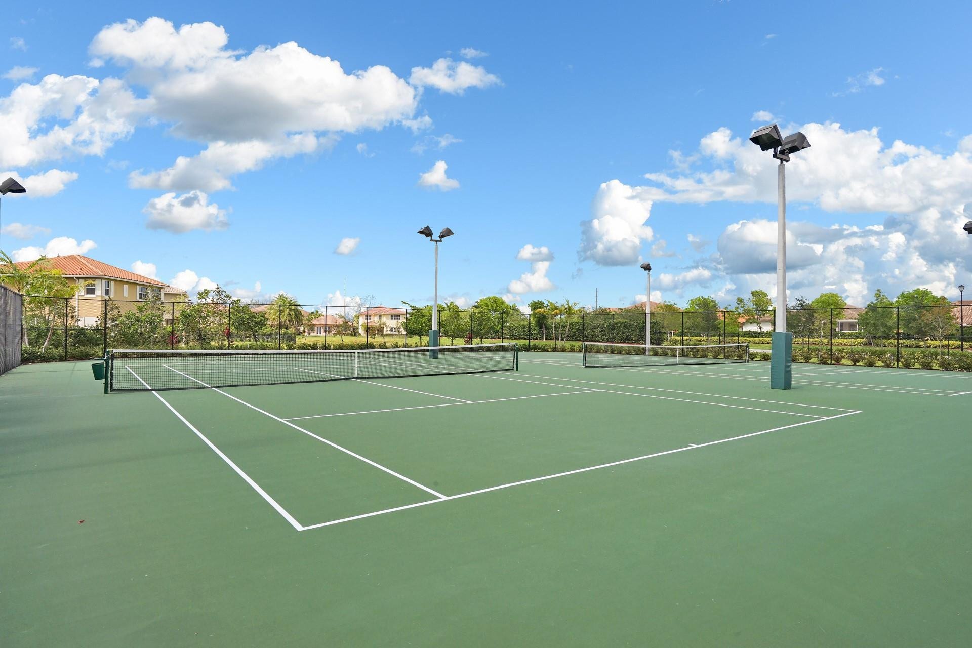 9749 Blue Isle, #BAY, Parkland, FL 33076 Two adjacent tennis courts featuring a green surface, white court lines, and chain-link fencing