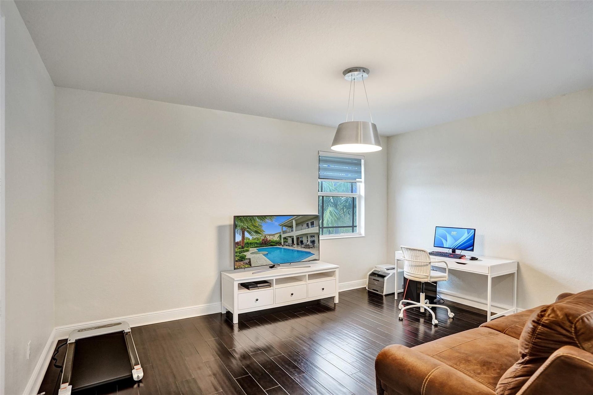 9749 Blue Isle, #BAY, Parkland, FL 33076 Spacious room featuring dark wood-finish flooring, a contemporary pendant light fixture, and a window with blinds