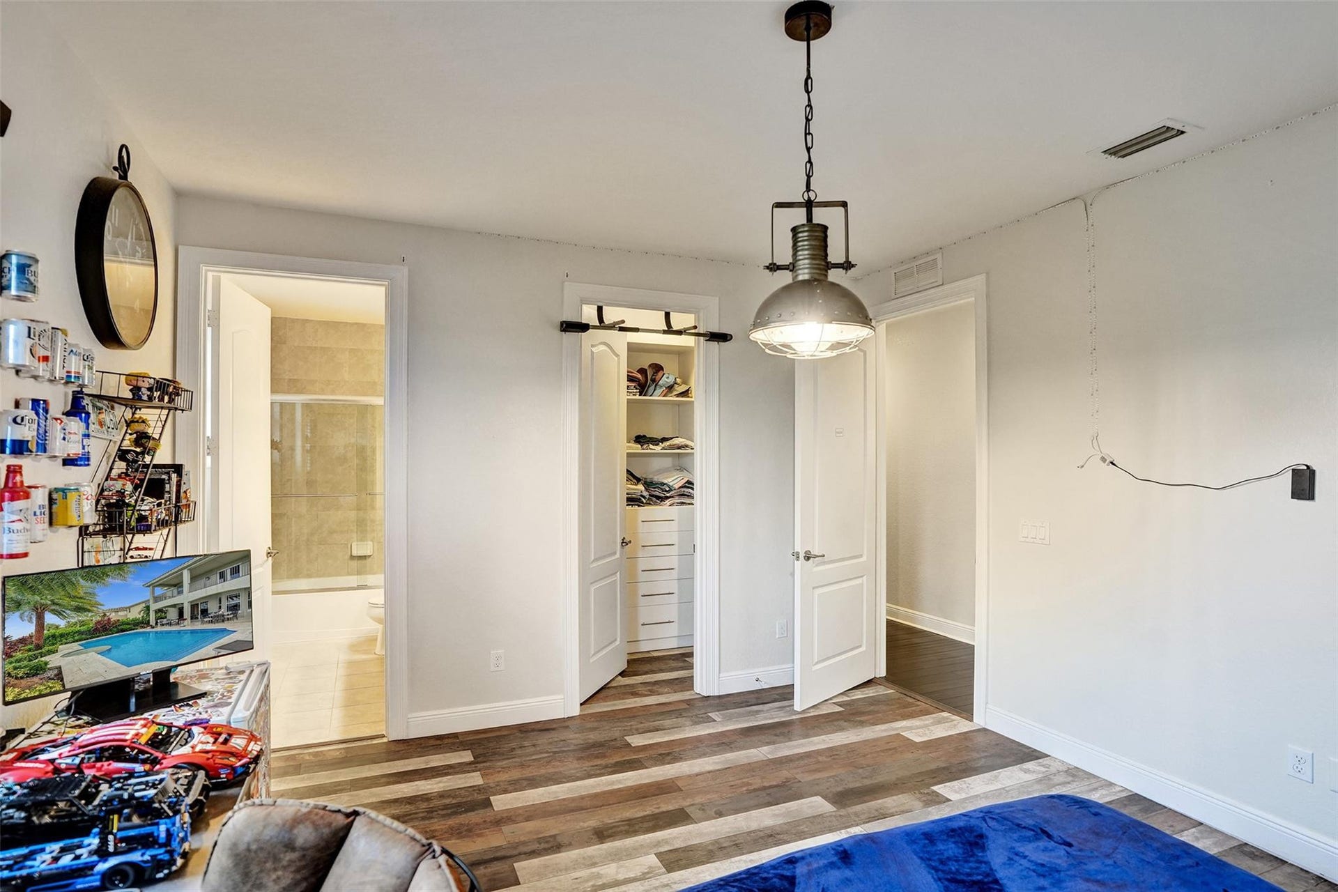 9749 Blue Isle, #BAY, Parkland, FL 33076 Wood-finish flooring, industrial-style pendant light fixture, white interior doors, and a built-in closet system