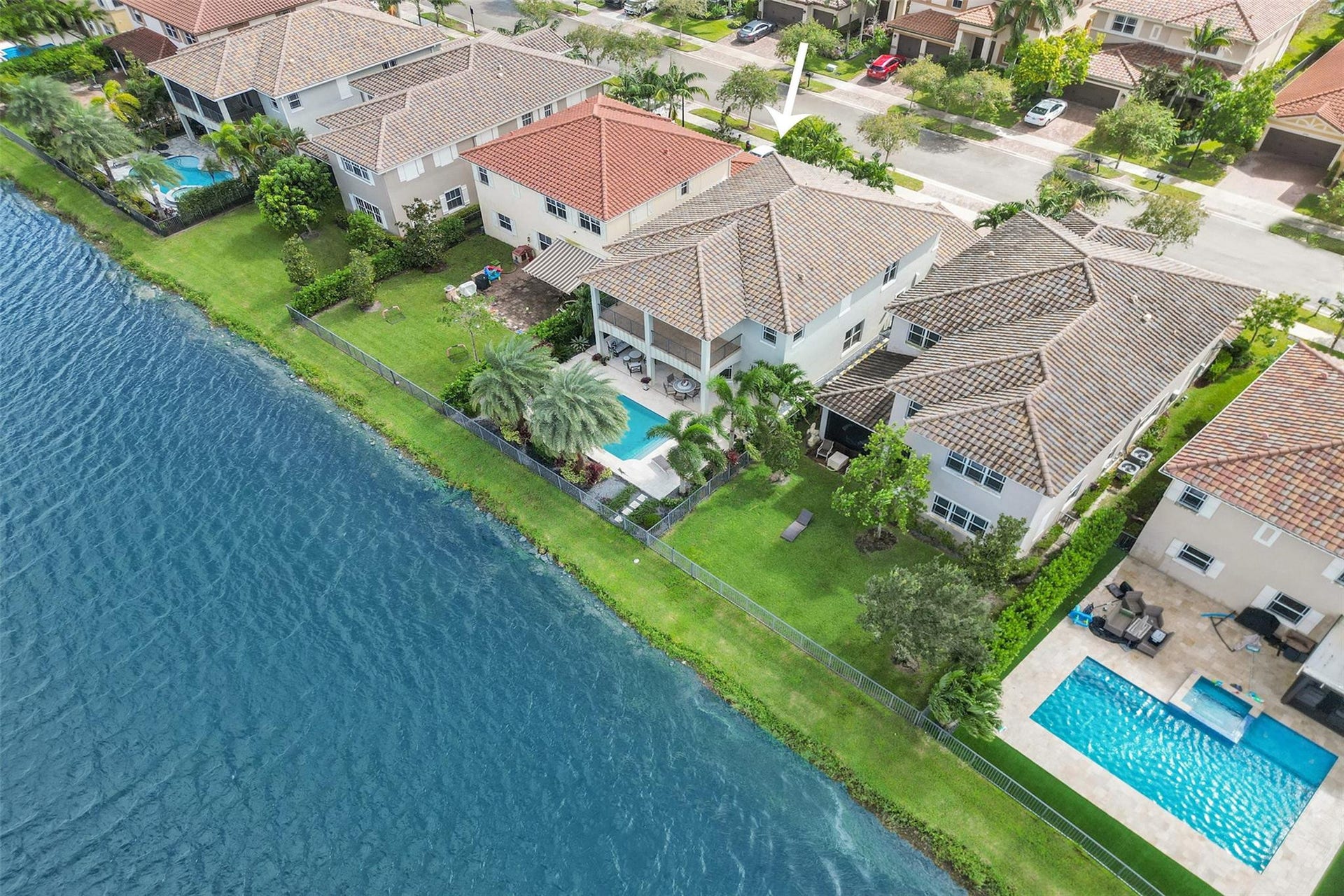 9749 Blue Isle, #BAY, Parkland, FL 33076 Waterfront property featuring a private swimming pool, covered patio, manicured lawn, and mature palm trees