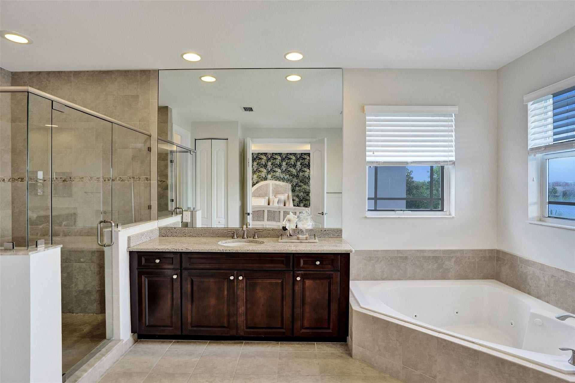 9749 Blue Isle, #BAY, Parkland, FL 33076 Glass-enclosed shower, dual-sink vanity with dark wood cabinetry, integrated jetted bathtub, recessed lighting, and tiled flooring