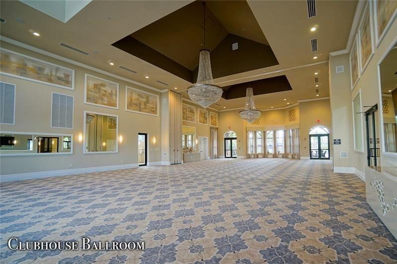 9749 Blue Isle, #BAY, Parkland, FL 33076 Expansive ballroom with patterned carpeting, dual tiered chandeliers, arched window and door openings, and recessed ceiling lighting