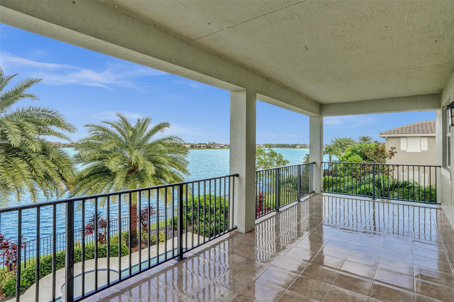 9749 Blue Isle, #BAY, Parkland, FL 33076 Covered outdoor patio with a tiled floor, black metal railings, and waterfront scenery