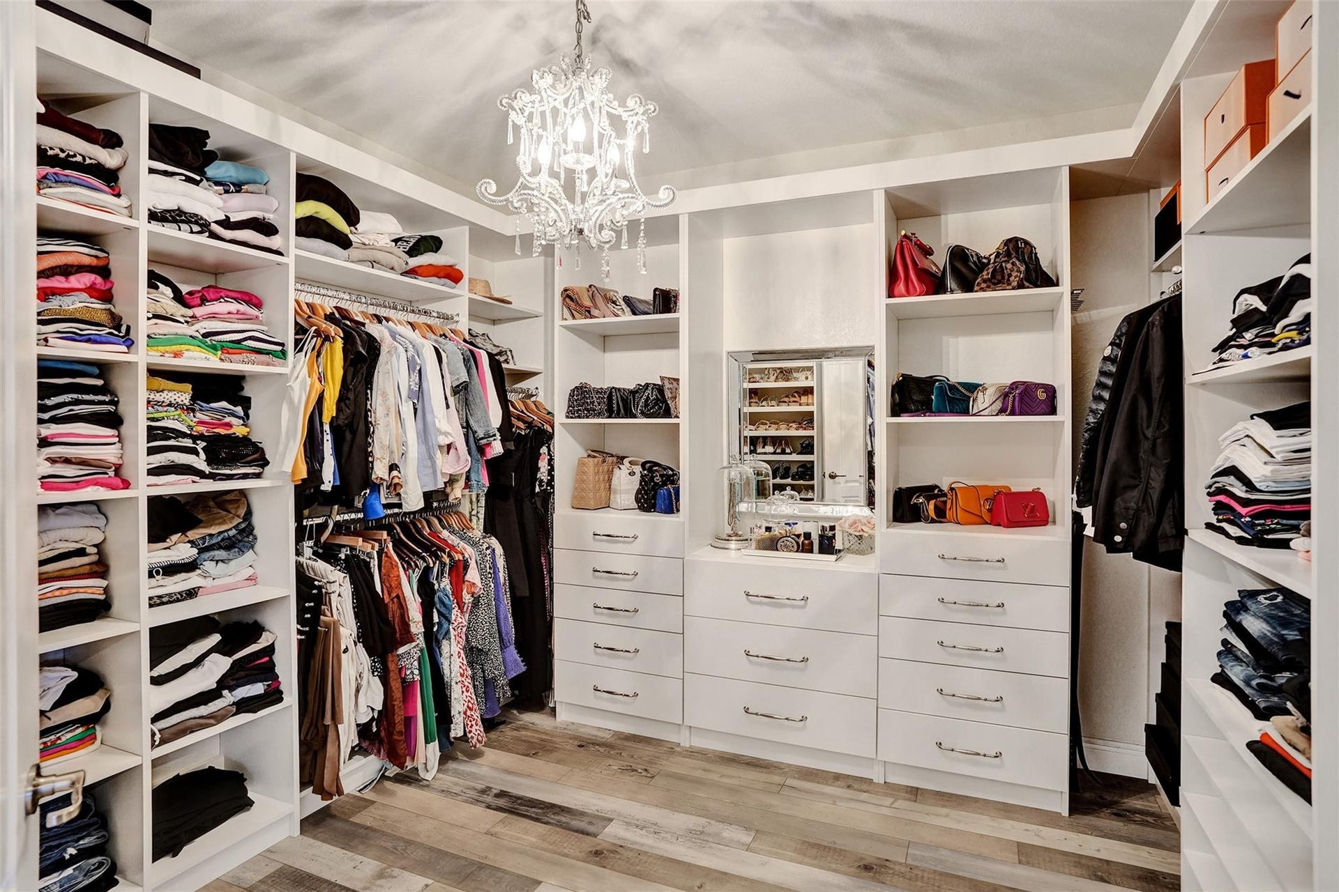 9749 Blue Isle, #BAY, Parkland, FL 33076 Built-in closet system featuring multiple shelves, hanging rods, drawers with hardware, and a chandelier