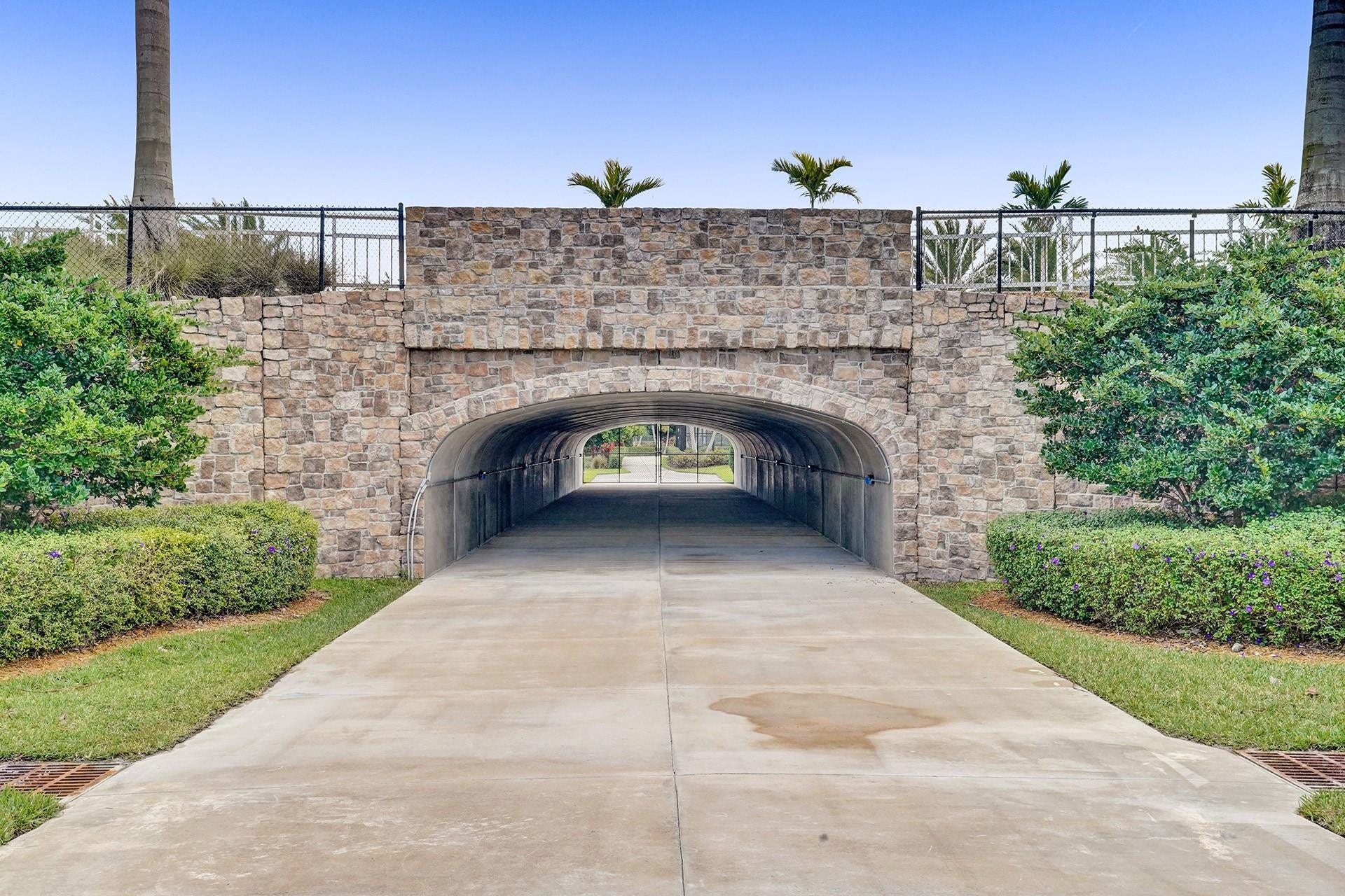 9749 Blue Isle, #BAY, Parkland, FL 33076 Stone-clad bridge with an arched underpass, bordered by manicured landscaping and a concrete pathway