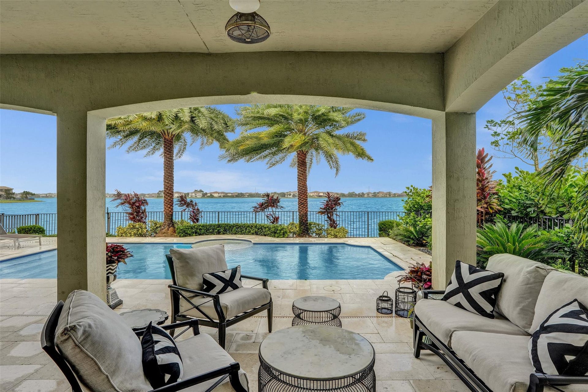 9749 Blue Isle, #BAY, Parkland, FL 33076 Covered patio with a ceiling fan, a swimming pool, and a body of water with a distant shoreline