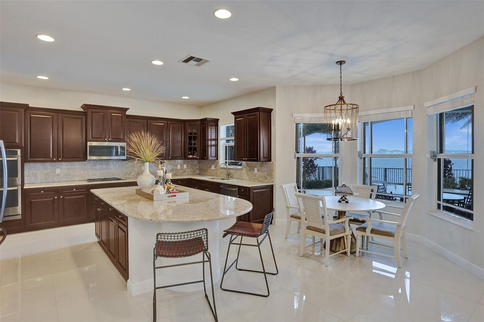 9749 Blue Isle, #BAY, Parkland, FL 33076 Kitchen featuring rich wood cabinetry, stainless steel appliances, a large center island with a light-toned countertop, and white tile flooring