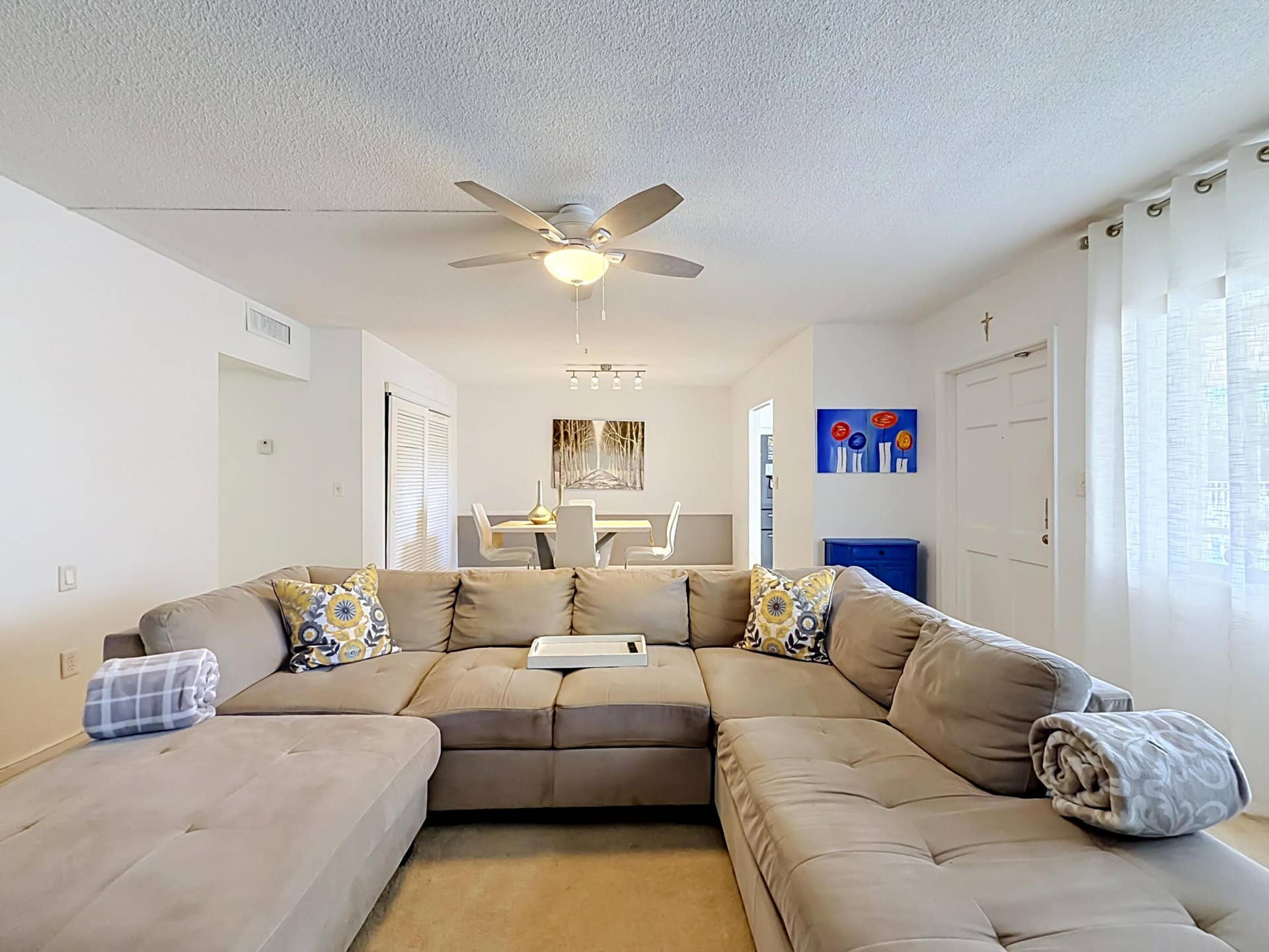 Recessed lighting illuminates the dining area, featuring a modern chandelier with four lights