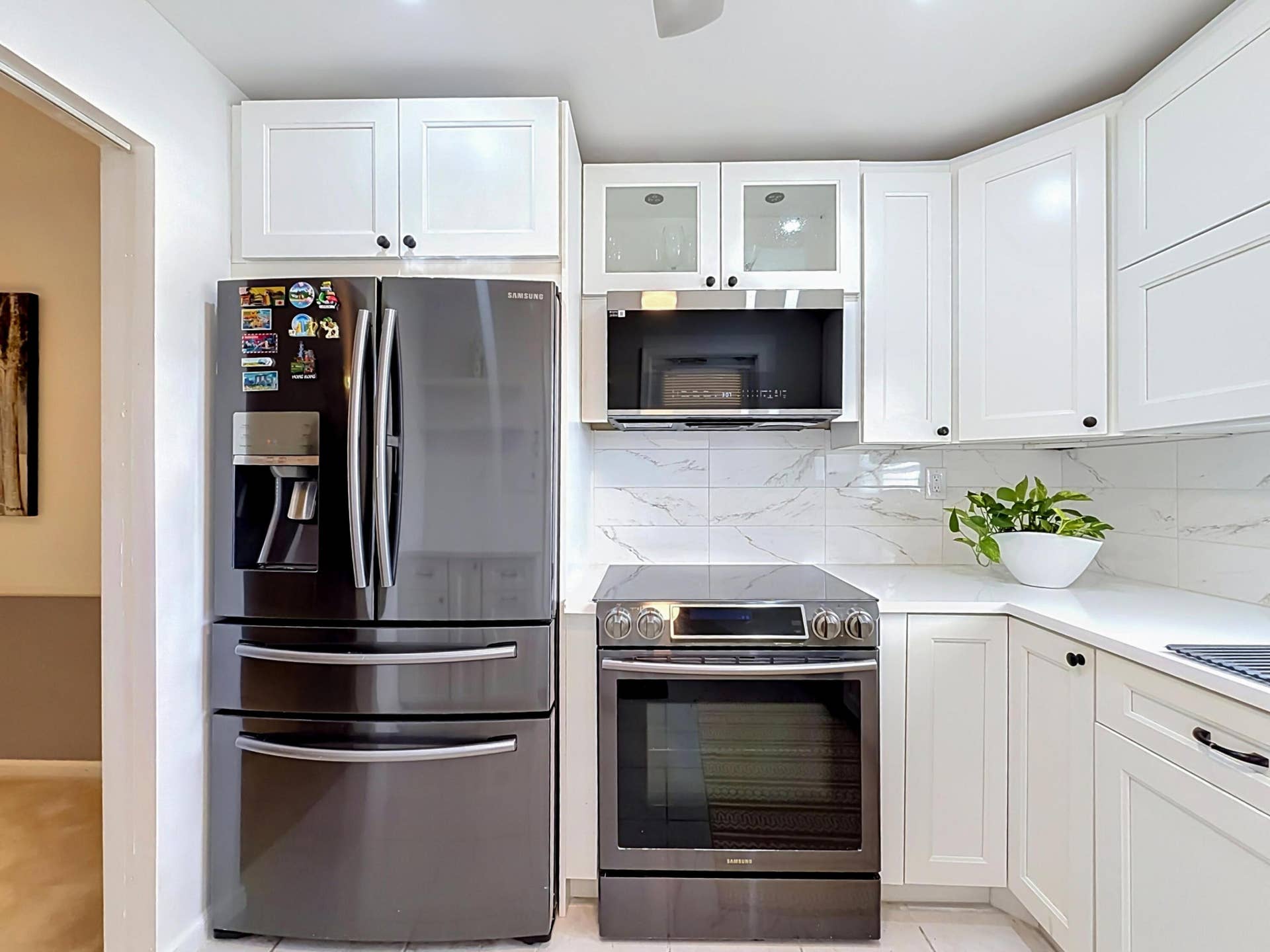 White shaker-style cabinetry with black hardware, white countertops, and a white tile backsplash