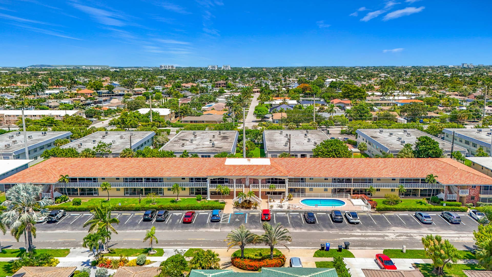 Multi-unit building featuring a terracotta tile roof, private balconies, and an outdoor swimming pool