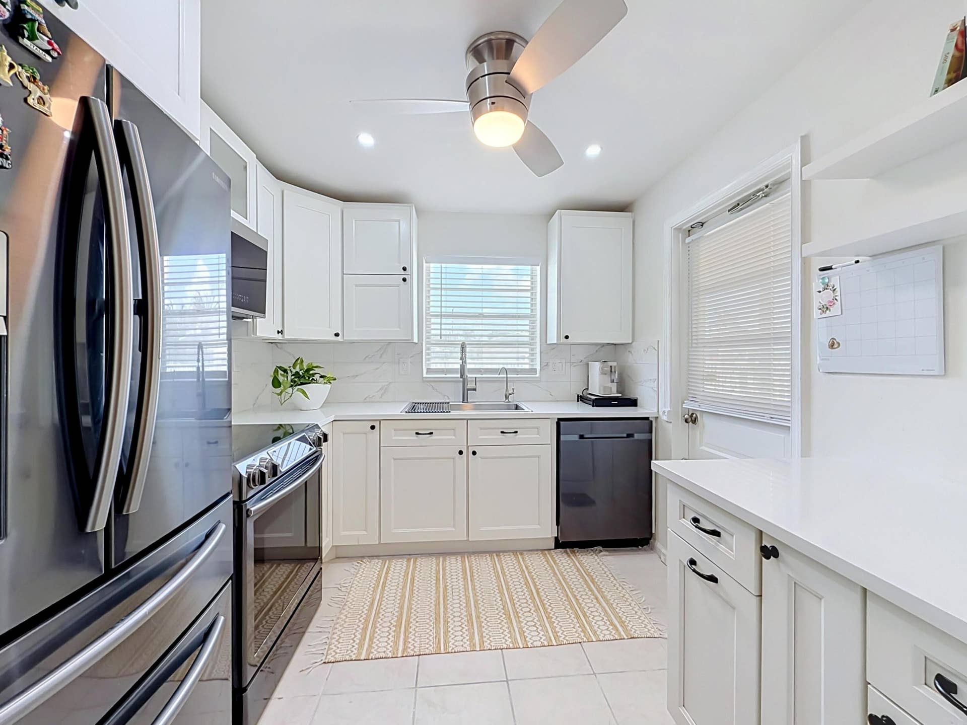 White shaker cabinetry, recessed lighting, ceiling fan with illumination, stainless steel appliances, and a solid surface countertop