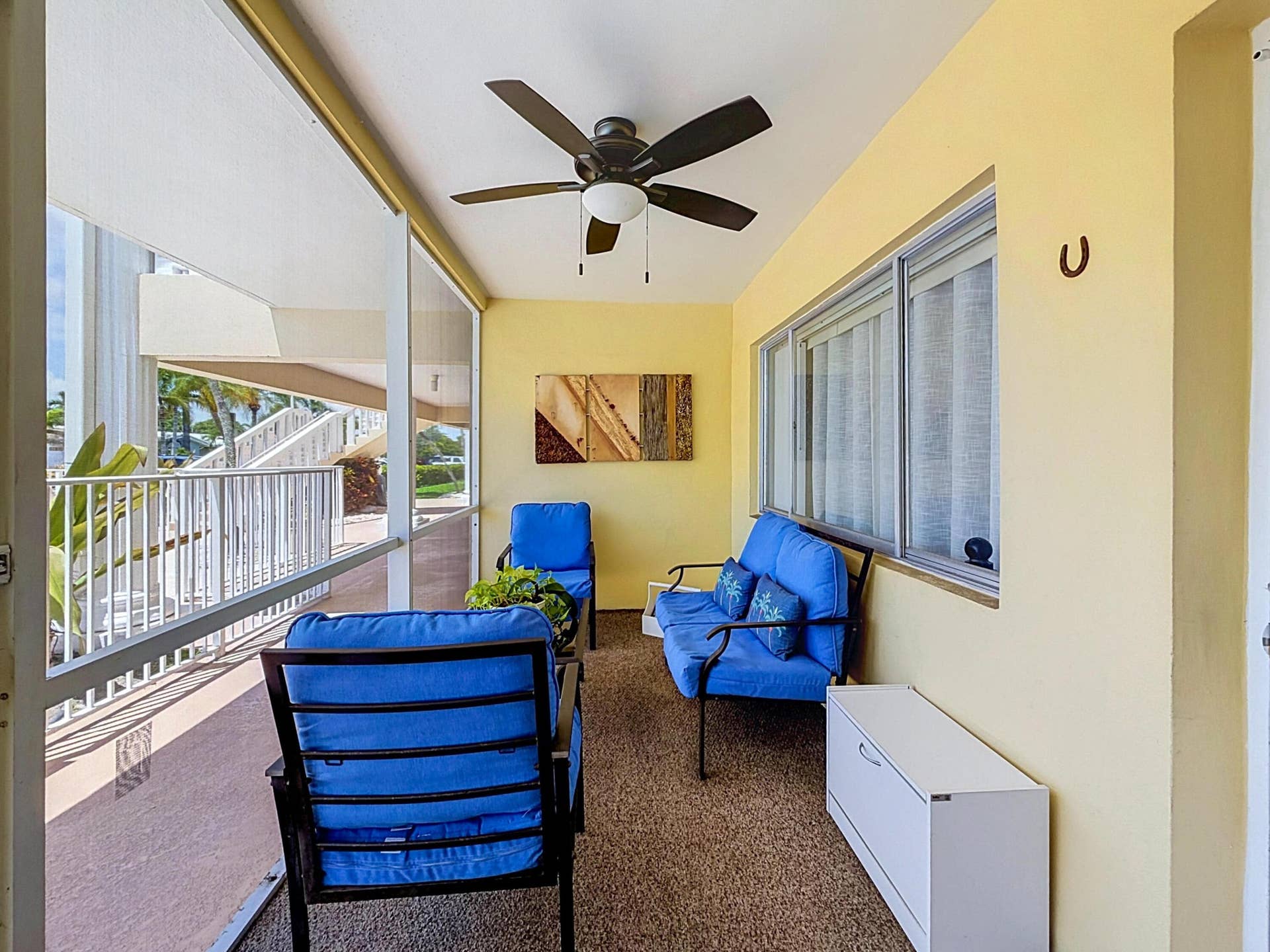 Screened outdoor living space featuring a ceiling fan, textured flooring, and a large window