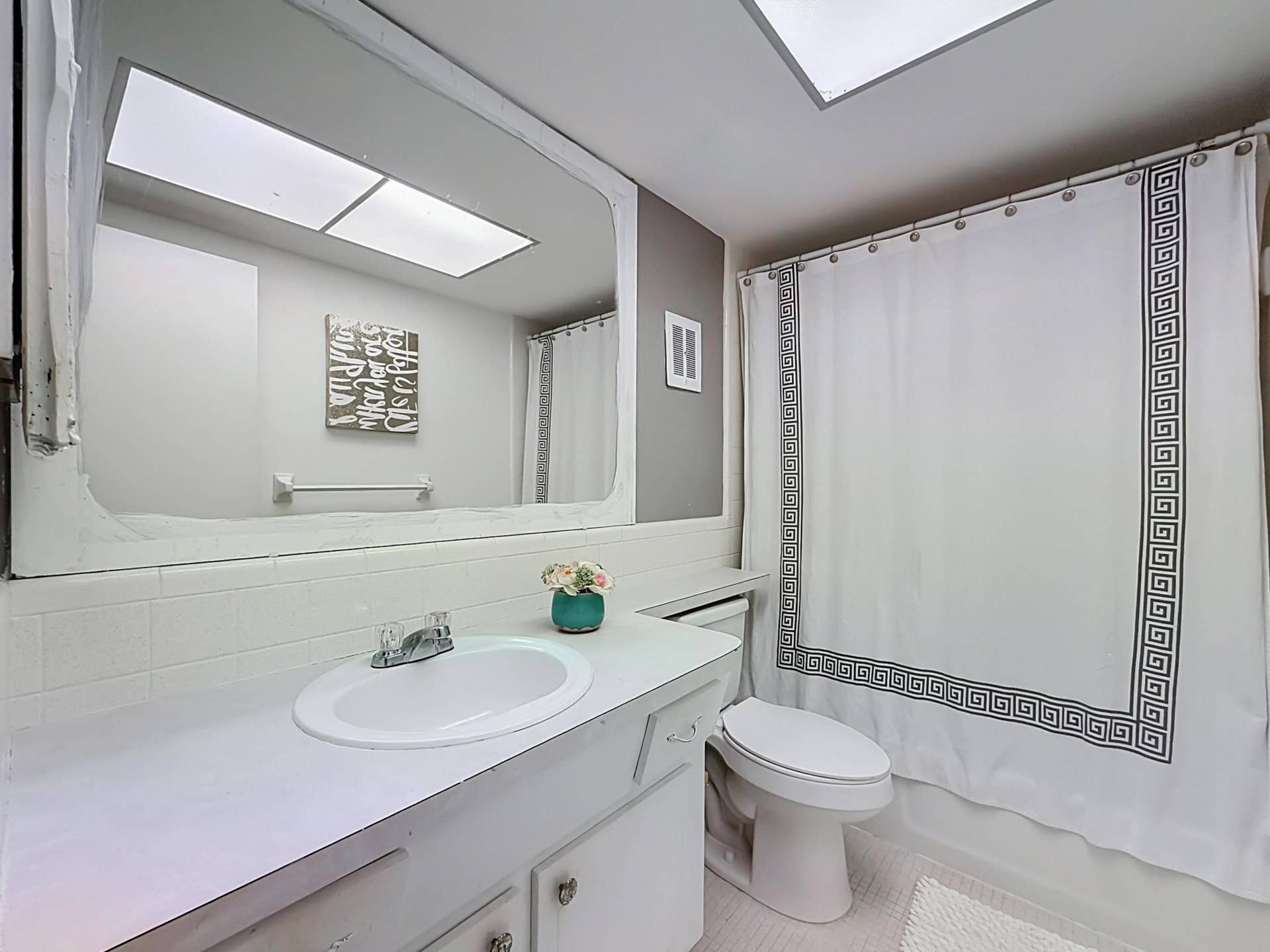 Integrated vanity with basin sink, mirrored wall, and overhead lighting