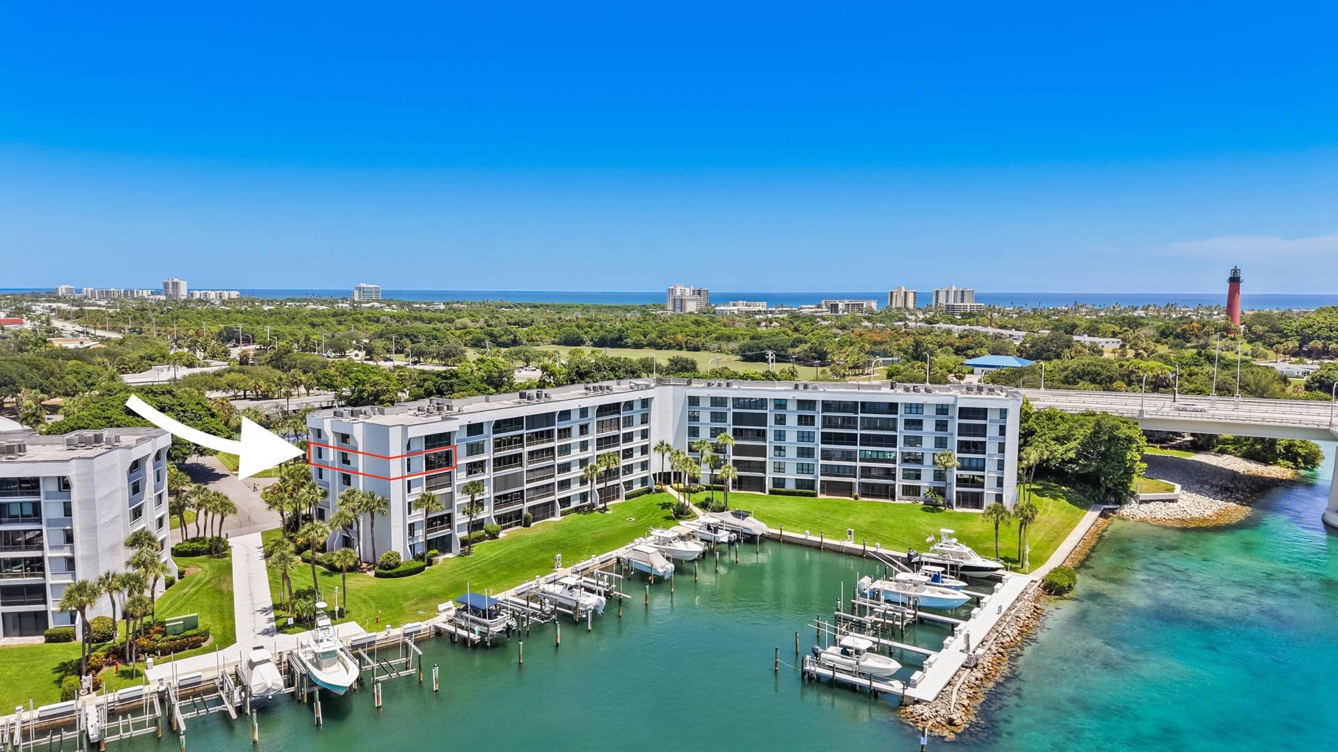 Waterfront condominium building with private boat docks, lush green landscaping, and direct water access