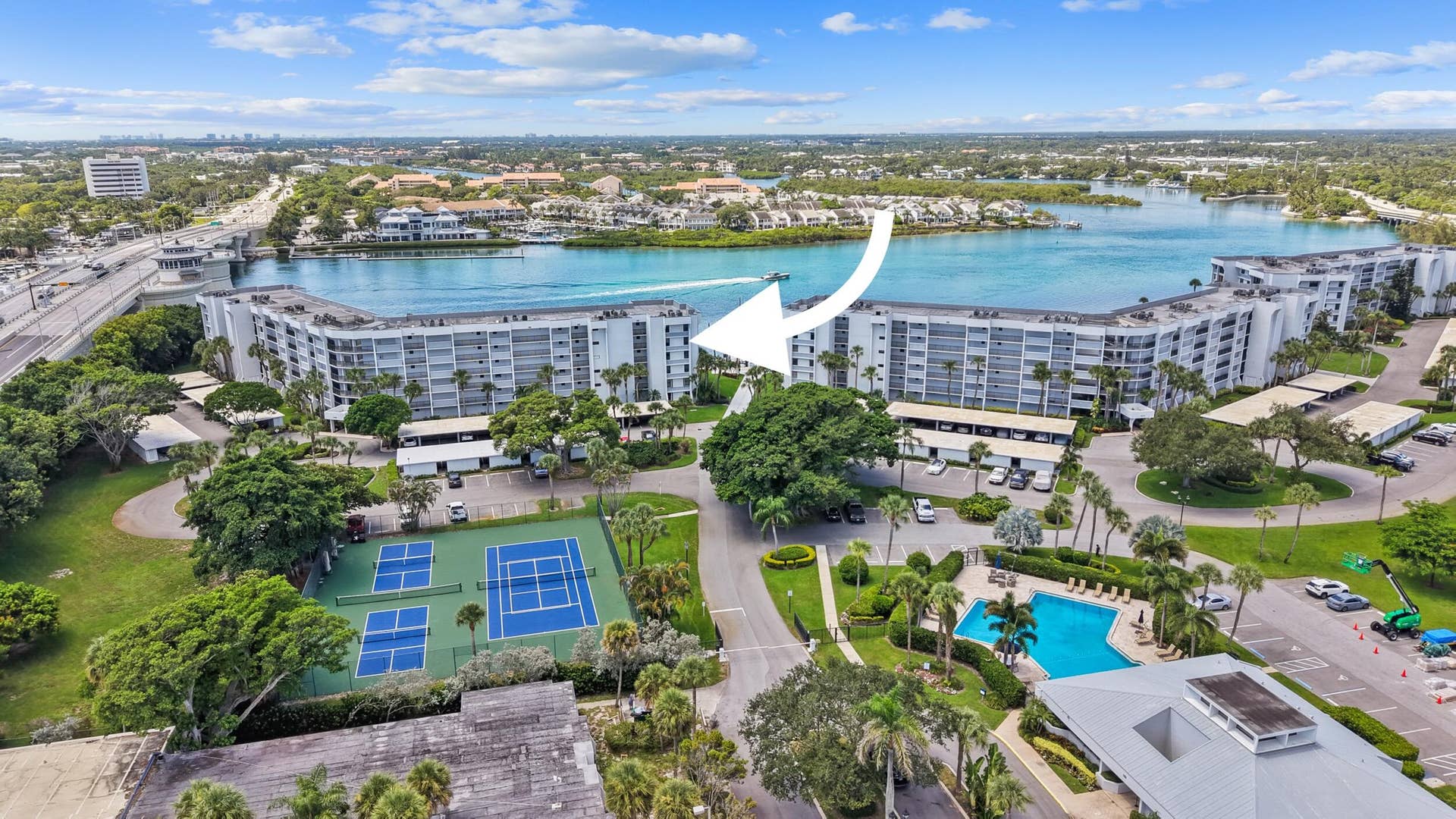 Waterfront property featuring multiple buildings, an outdoor swimming pool, and dedicated tennis courts