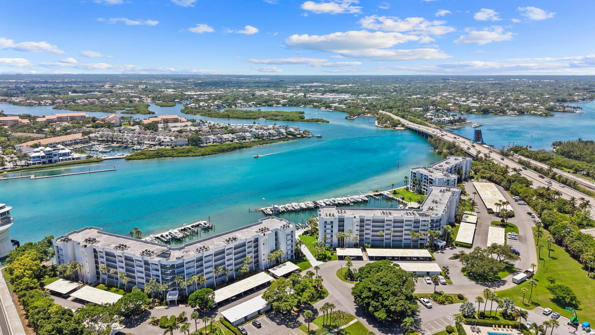 Waterfront condominium complex with private boat docks, covered parking structures, and lush tropical landscaping