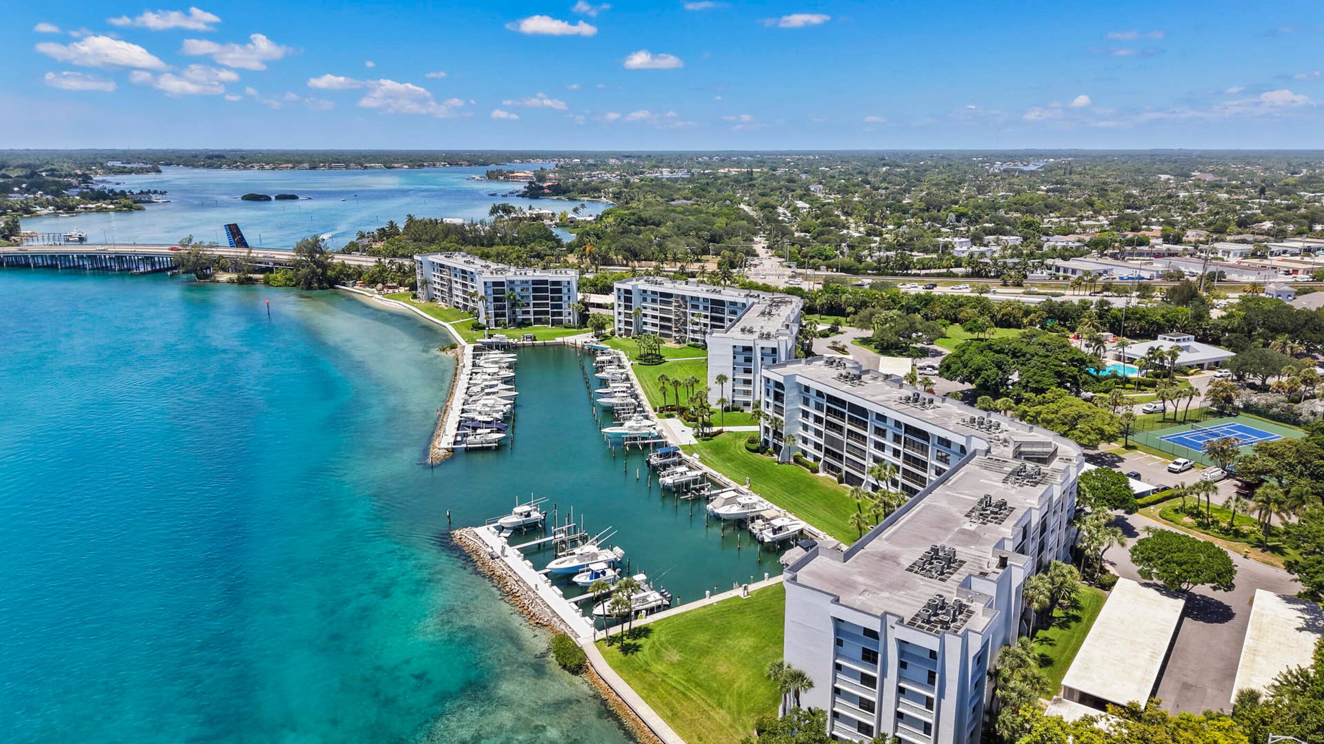 Waterfront residential complex featuring modern multi-unit architecture with direct marina access, private boat slips, manicured landscaping, and expansive water views overlooking the bay and surrounding coastal community