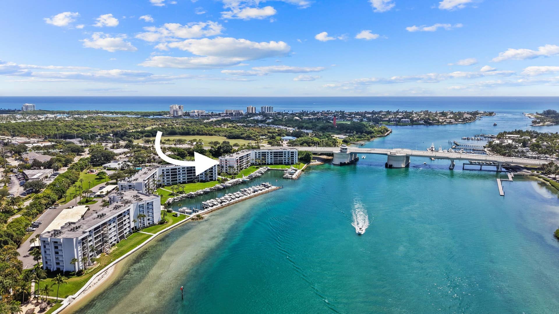 Waterfront condominium complex with private boat slips, surrounding water, and nearby bridge access