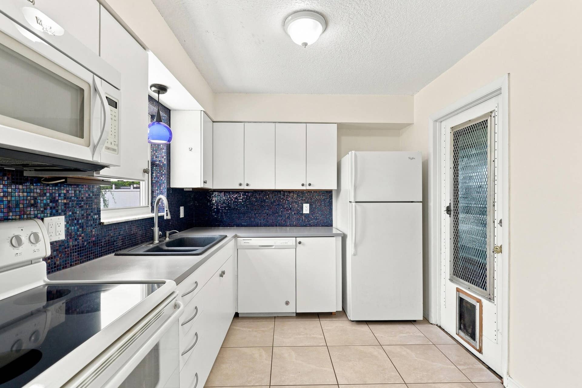 5114 Conklin Drive, Delray Beach, FL 33484 Functional kitchen with white cabinetry, generous storage, and access to the exterior.