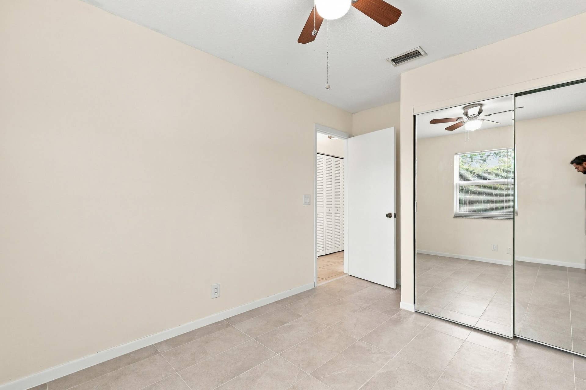 5114 Conklin Drive, Delray Beach, FL 33484 Bedroom featuring a ceiling fan, neutral flooring, and mirrored closet doors.