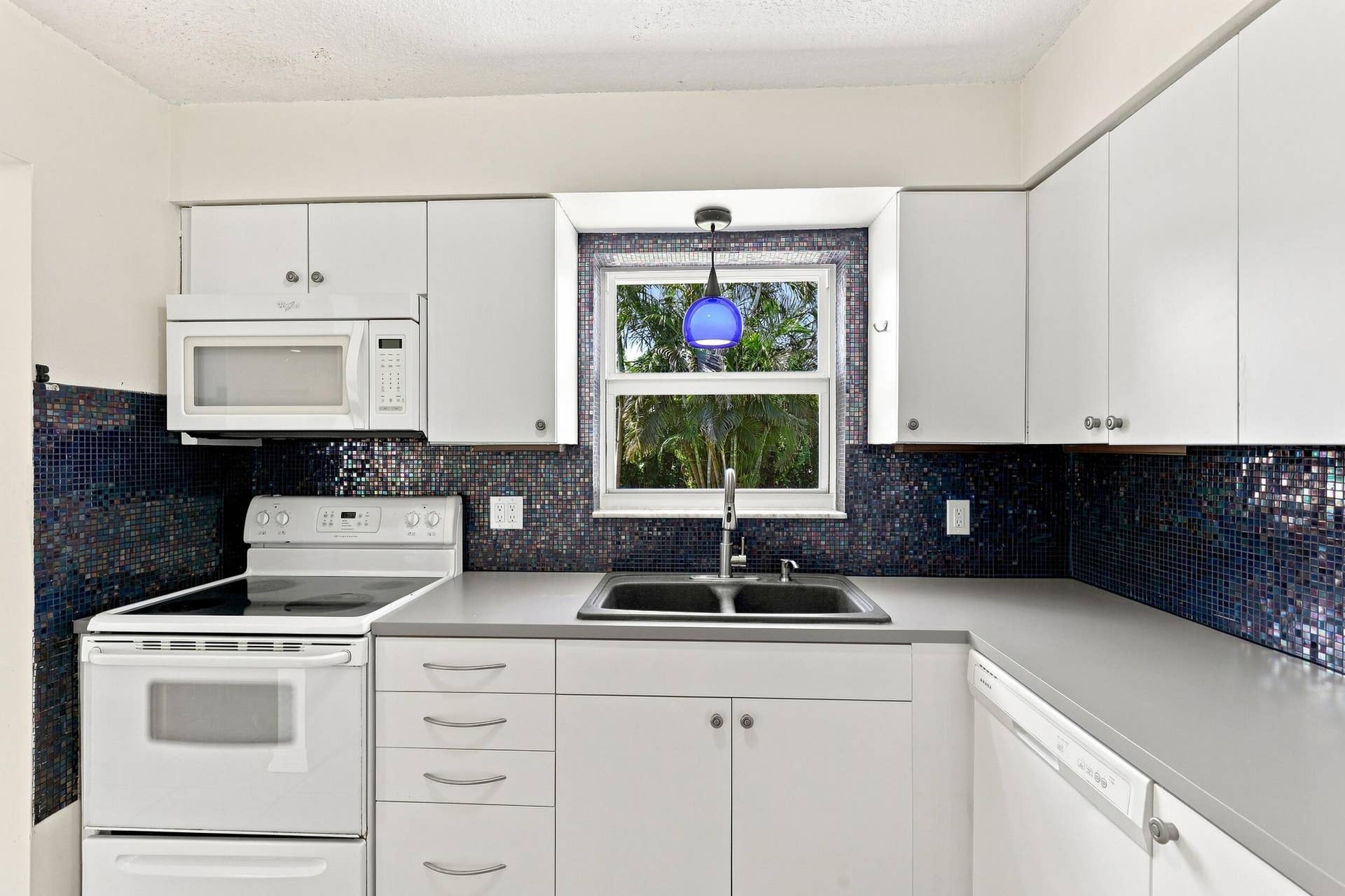5114 Conklin Drive, Delray Beach, FL 33484 Kitchen featuring white cabinetry, ample counter space, and a window above the sink.