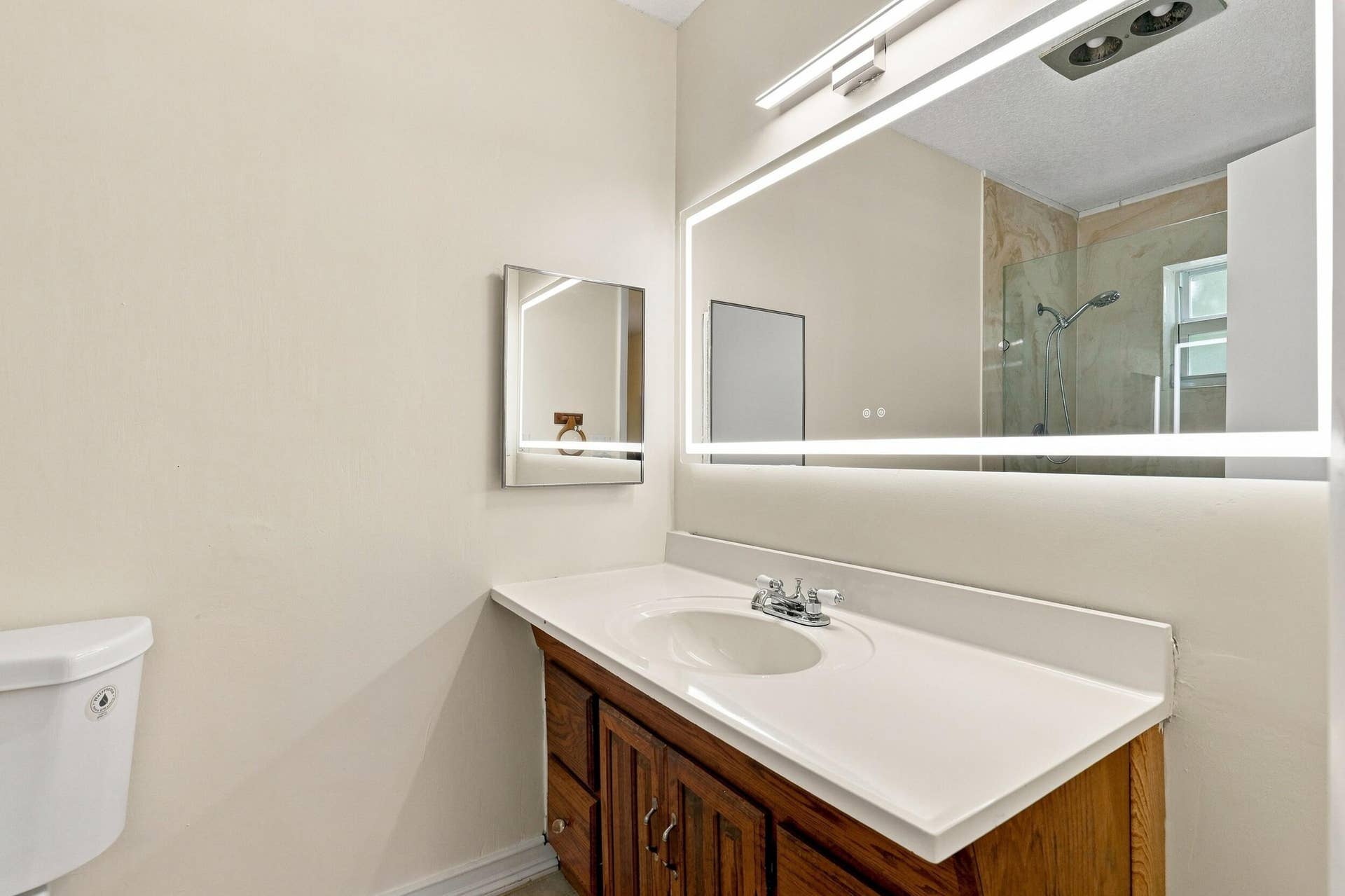 5114 Conklin Drive, Delray Beach, FL 33484 Bathroom featuring a wood vanity, large mirror, and bright overhead lighting.