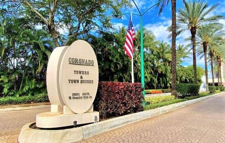 20335 W COUNTRY CLUB Drive, #2408, Aventura, FL 33180 Entrance sign for Coronado Towers & Town Houses, surrounded by lush landscaping, mature palm trees, and a paved driveway