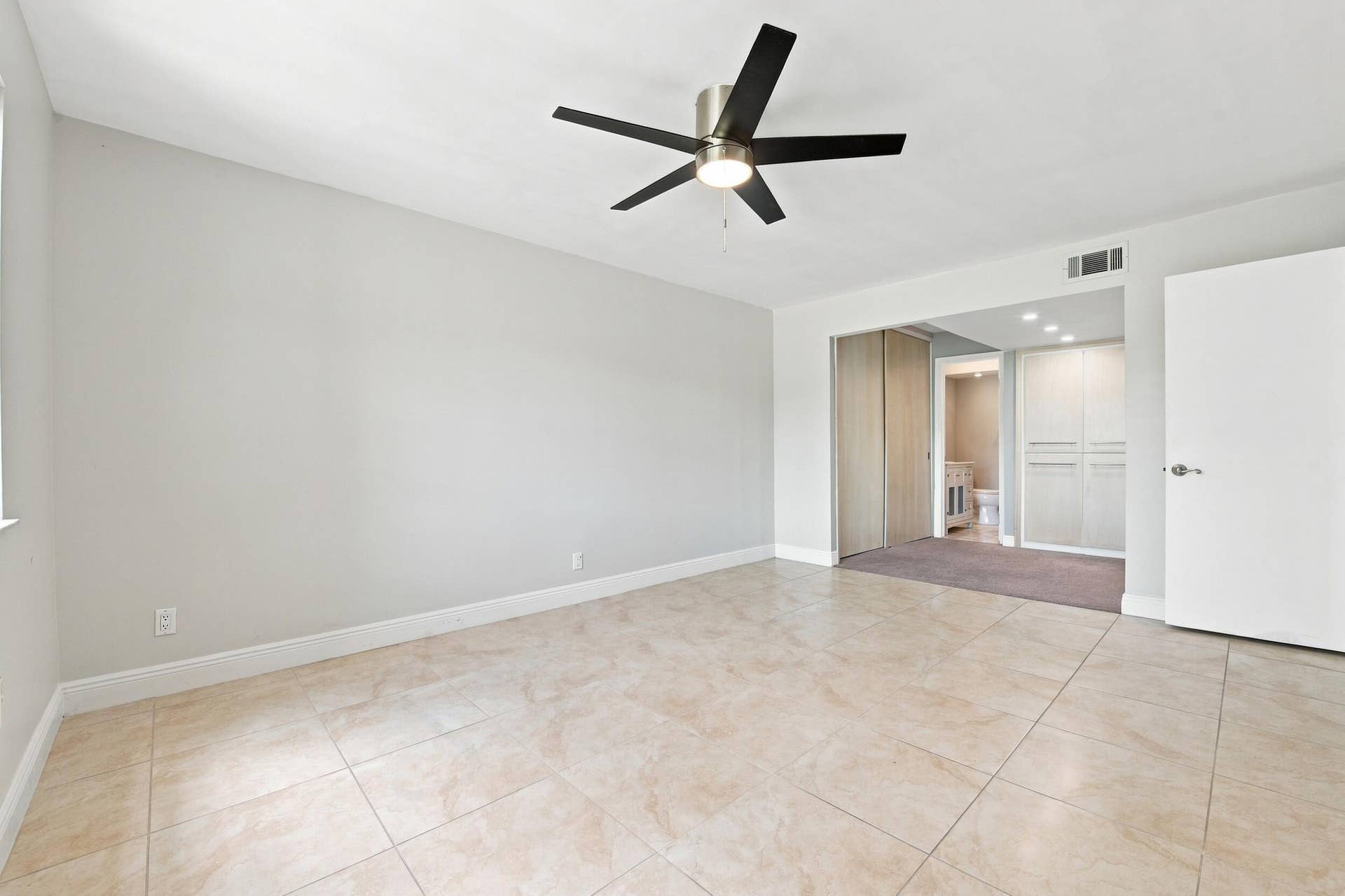 Spacious room featuring vaulted ceilings, a ceiling fan with integrated lighting, and light-toned tile flooring