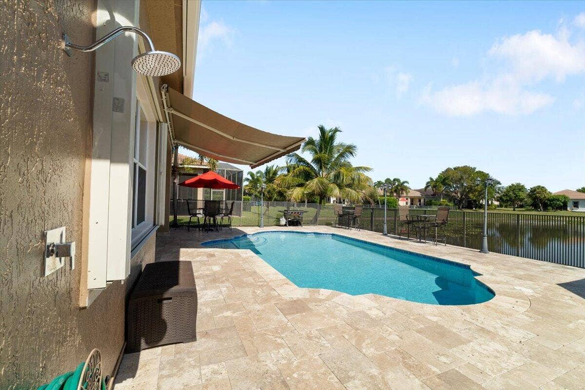 12390 NW 78th Manor, Parkland, FL 33076 come and take a swim in this cool pool in our fully fenced Jerusalem travetine paved patio, Notice the strong top of the line hurricane impact accordion quick shutters,