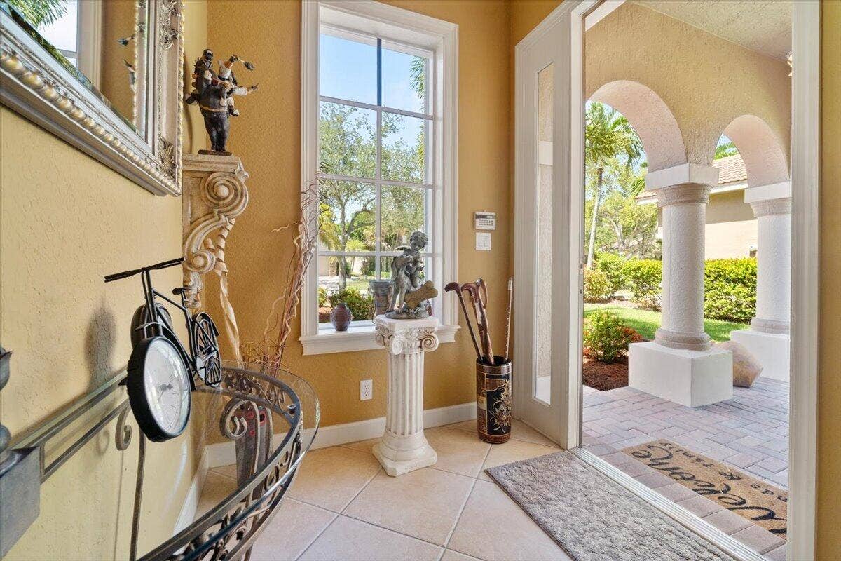 12390 NW 78th Manor, Parkland, FL 33076 The front door entryway as you come inside, there is a pavered porch patio with coloms to sit and enjoy the views of the front garden and flowers,