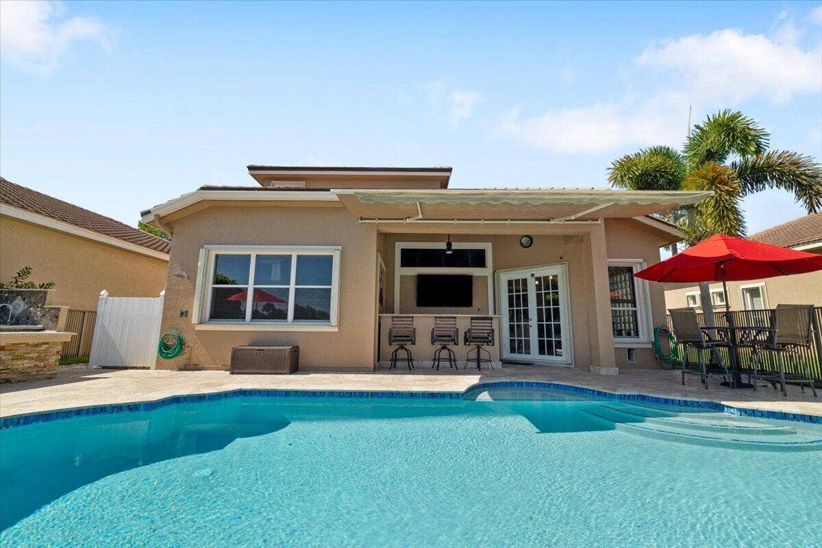 12390 NW 78th Manor, Parkland, FL 33076 The view onto the entertainment patio from inside the iron fence & lake, Exterior recently painted,