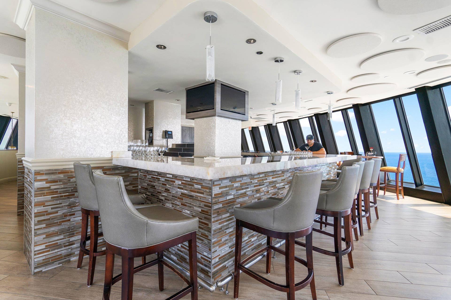 Bar seating at Tiaras Marque restaurant offers a relaxed setting for drinks and dining, surrounded by elevated water views.