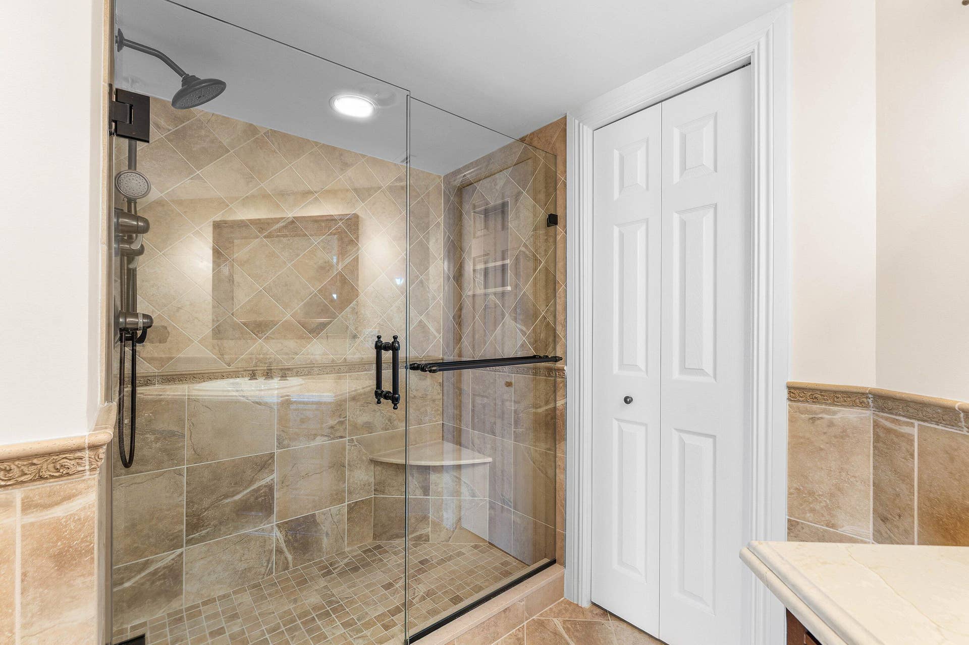 The primary bathroom combines a substantial vanity, tiled finishes and a glass-enclosed shower to create a comfortable, well-appointed en-suite retreat.