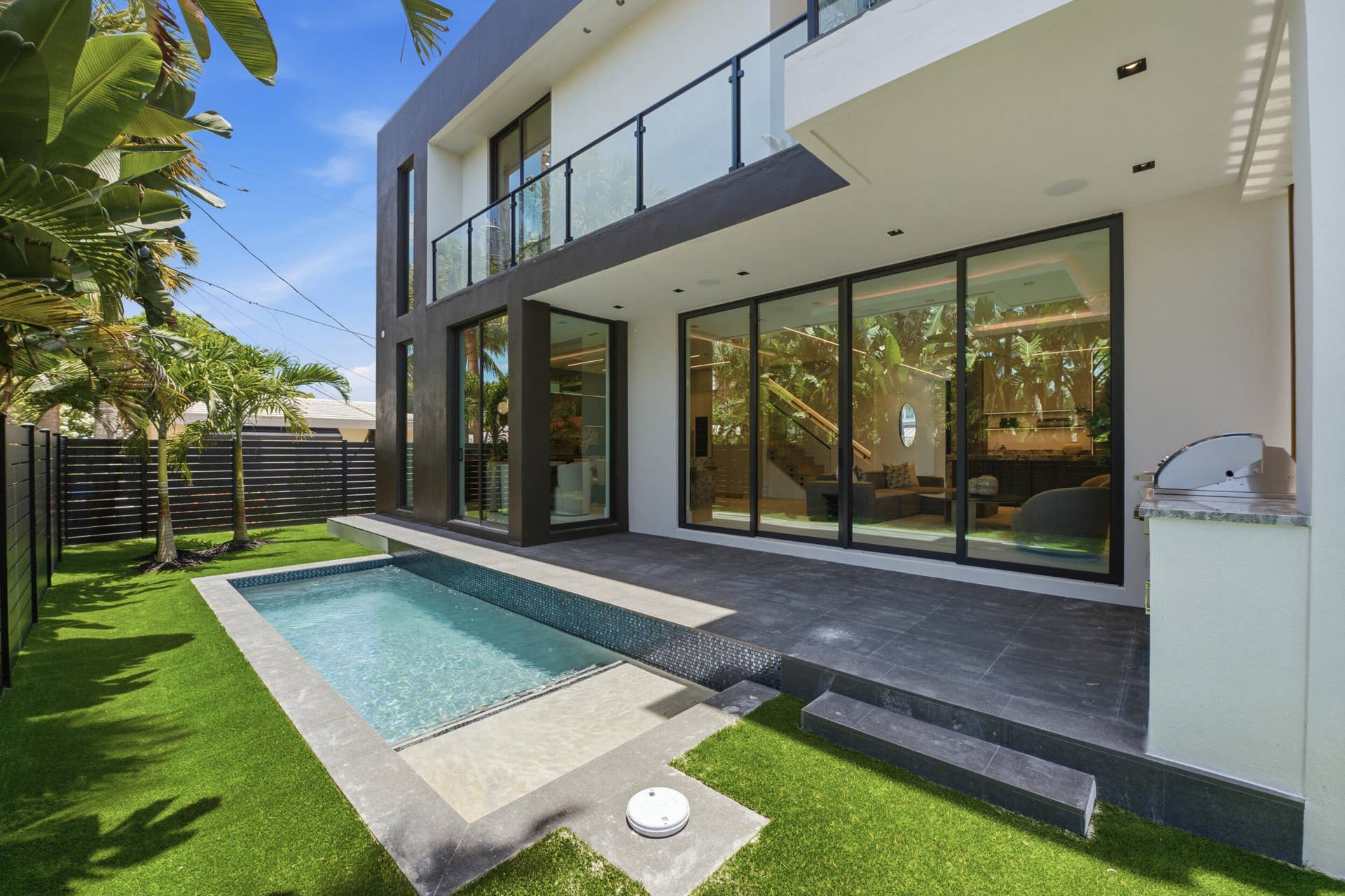 Modern exterior with a private swimming pool, expansive patio, artificial turf, and an outdoor grilling station