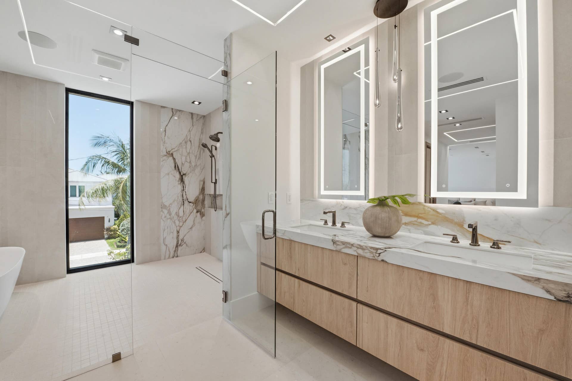 Dual floating vanity with wood-finish cabinetry, integrated sinks, and backlit mirrors