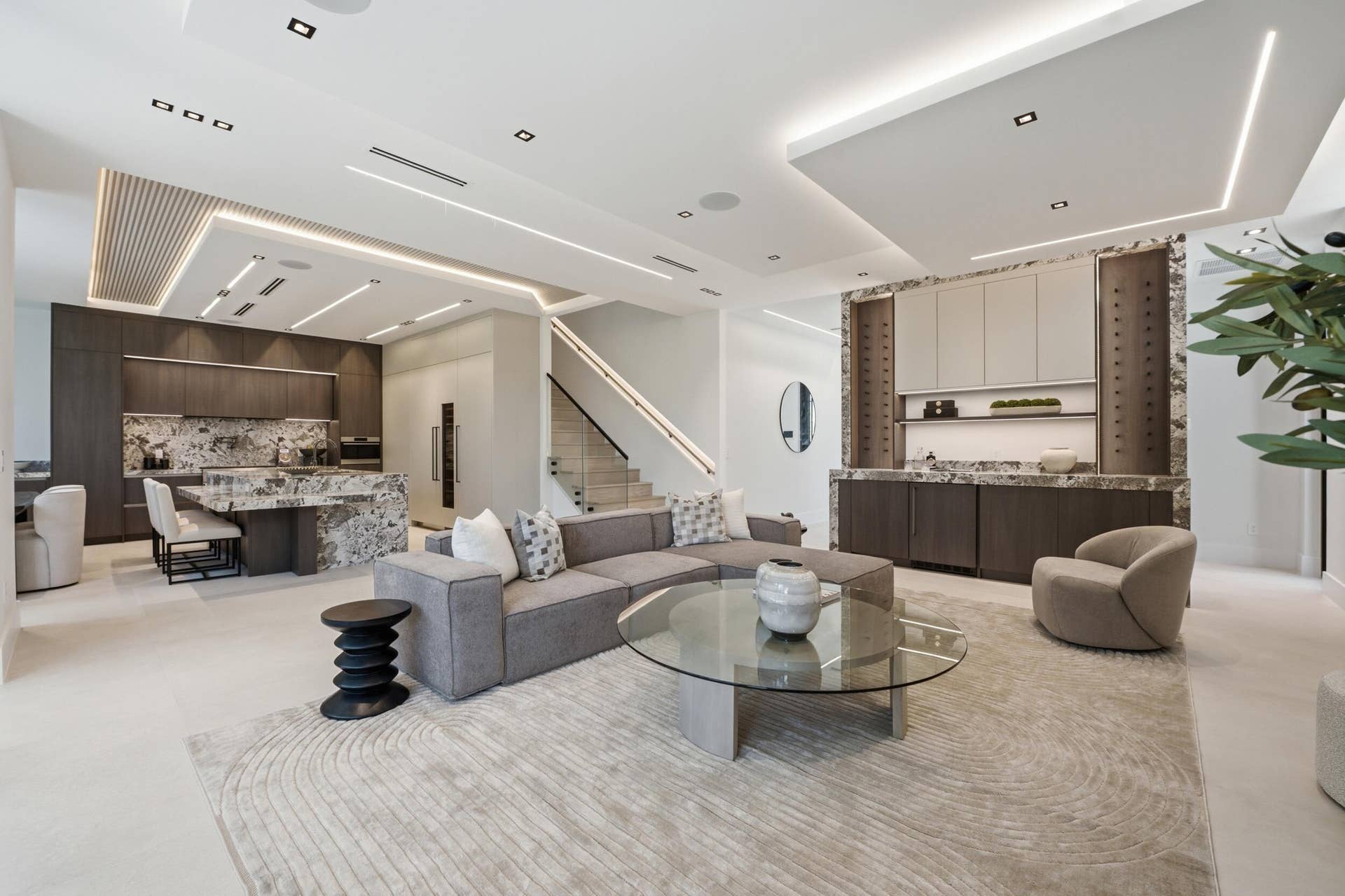 Open-concept living area with integrated kitchen, custom built-in bar, and a modern staircase
