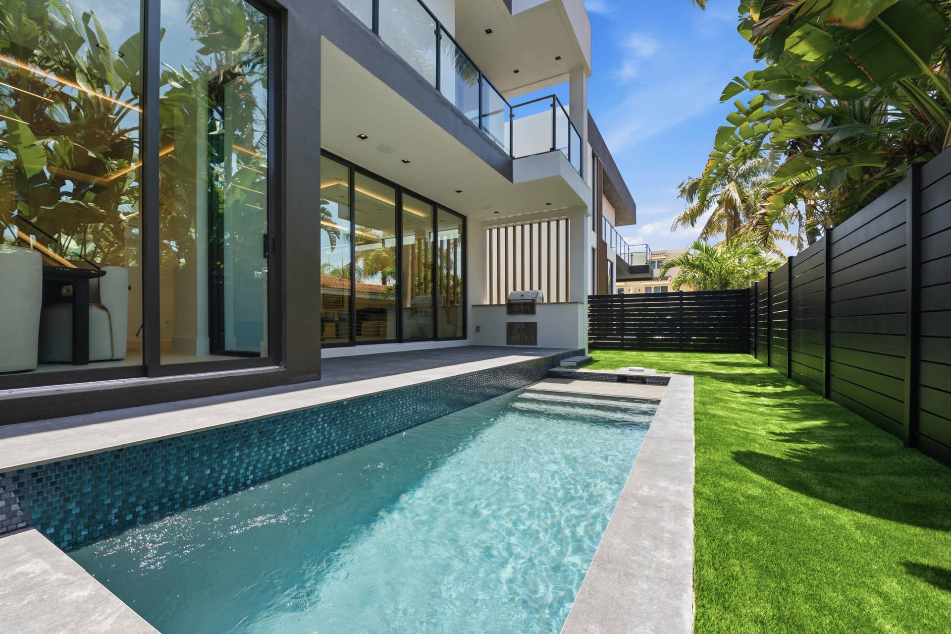 Modern exterior with a rectangular swimming pool, integrated spa steps, and a built-in outdoor grill station