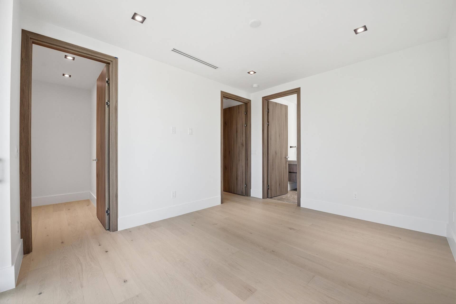 Light wood-finish flooring with crisp white walls and recessed ceiling lighting