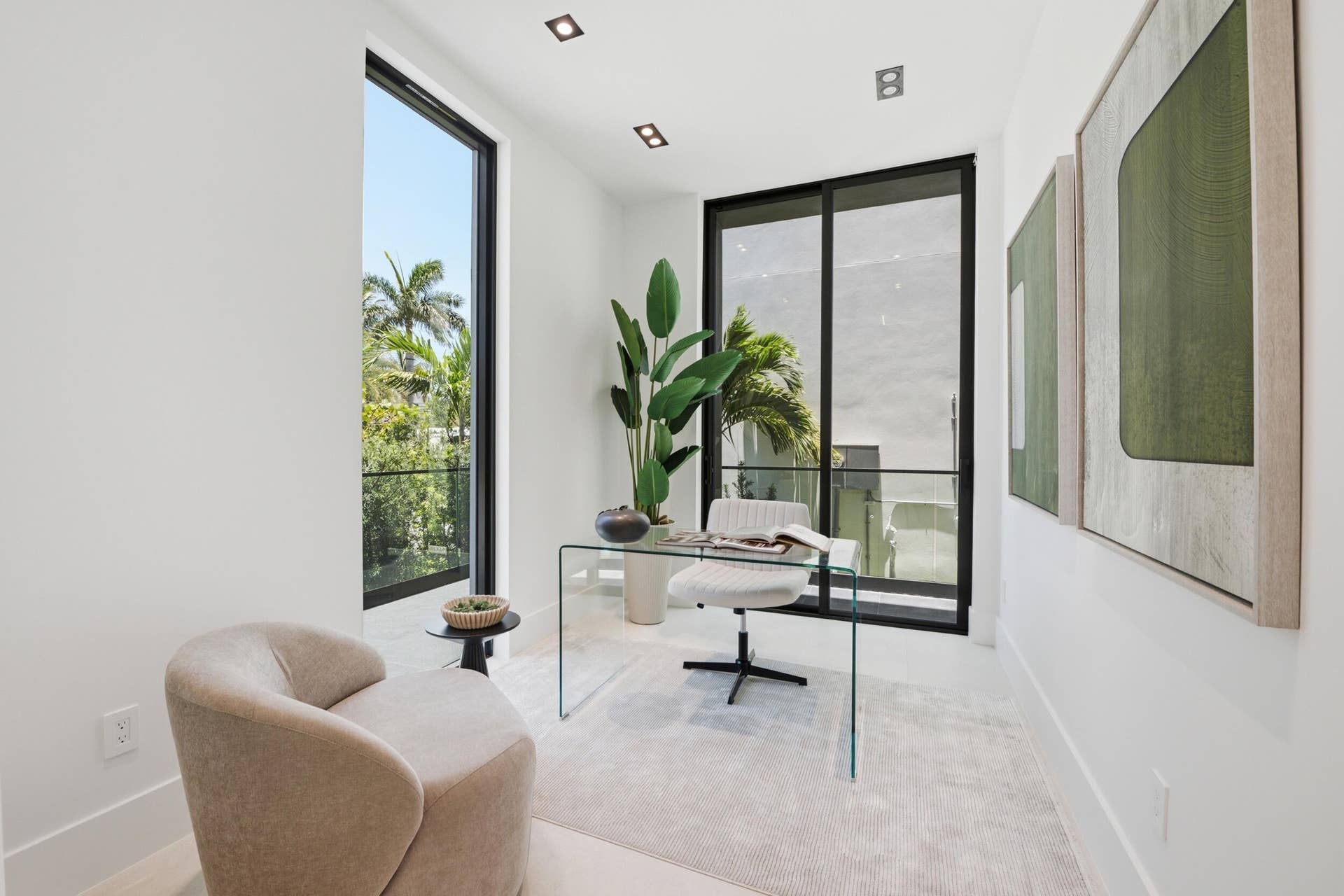 White interior walls, recessed ceiling lighting, light-toned flooring, and expansive windows with black framing