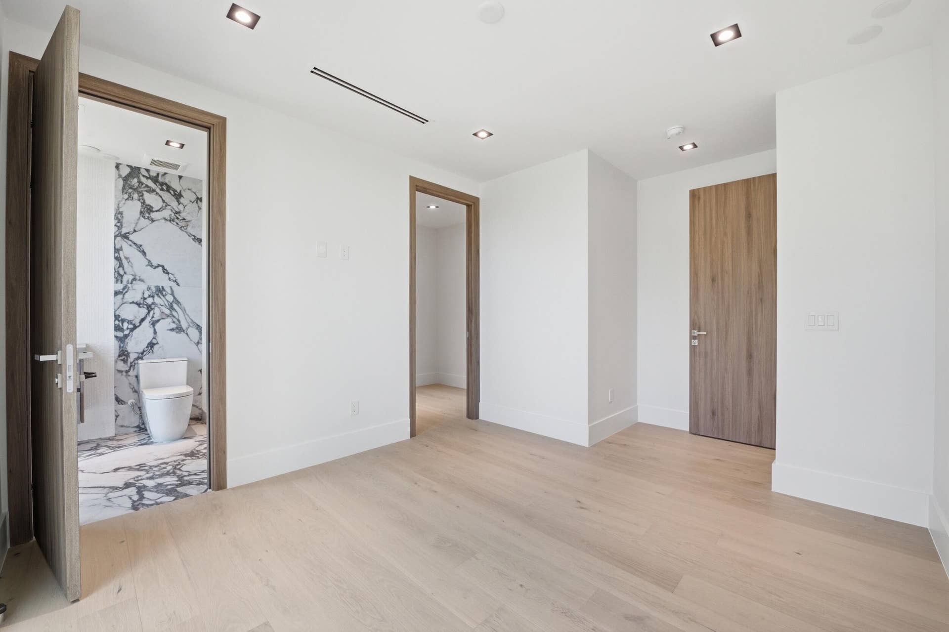 Light wood-finish flooring, recessed ceiling lighting, and solid wood interior doors