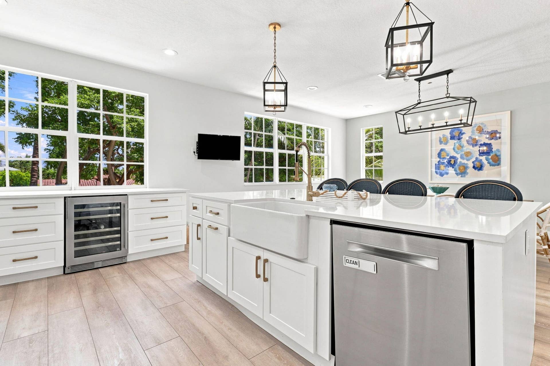 Kitchen featuring white cabinetry, light-toned luxury vinyl flooring, a white farmhouse sink, stainless steel dishwasher and built-in beverage refrigerator
